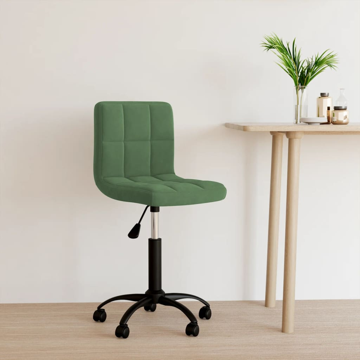 Ein grüner Bürostuhl mit schwarzem Gestell und Rollen steht neben einem Holztisch mit Pflanzen und Flaschen.