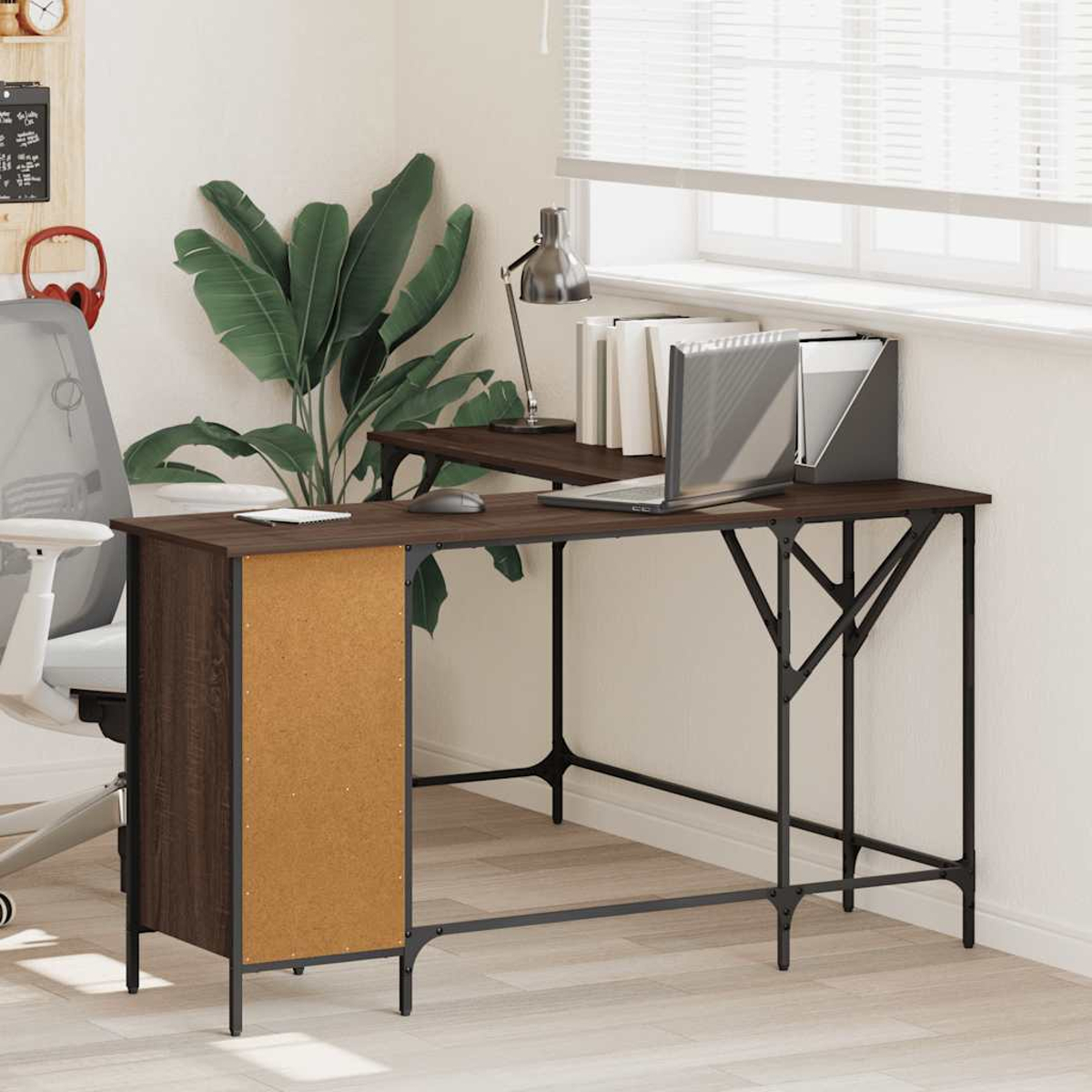Ein dunkelbrauner Schreibtisch mit Laptop, Lampe und Büchern. Eine Pflanze steht hinter dem Schreibtisch. Links ein weißer Stuhl.