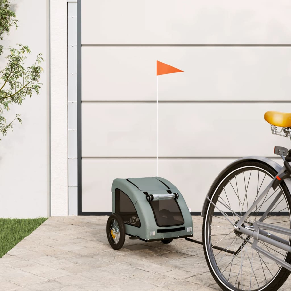 Ein Fahrrad mit Anhänger, orangefarbene Flagge am Anhänger und gelbem Sattel. Im Hintergrund ist ein weißes Garagentor.