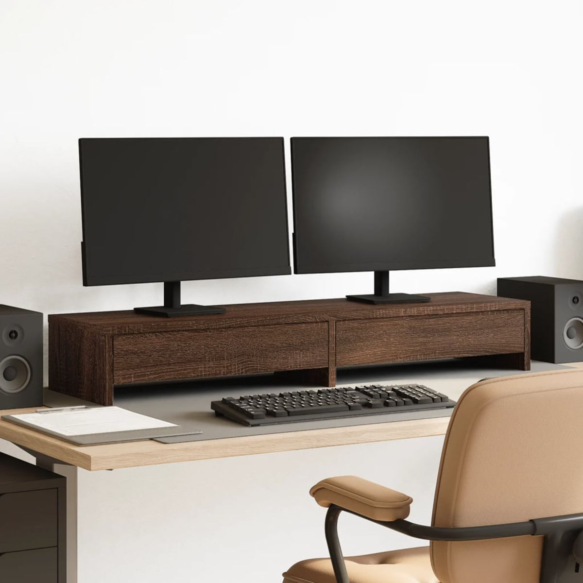 Zwei schwarze Monitore stehen auf einem braunen Schreibtisch. Tastatur, Lautsprecher und Bürostuhl sind sichtbar.