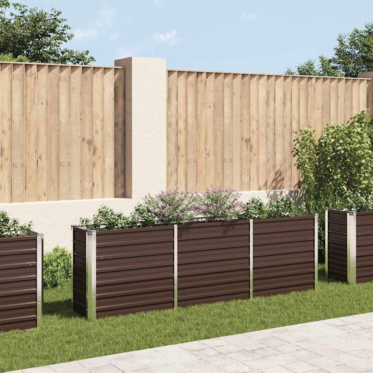 Braune Metallpflanzkästen mit Pflanzen auf grünem Gras, Holzzaun und Betonweg in einer Gartenumgebung.