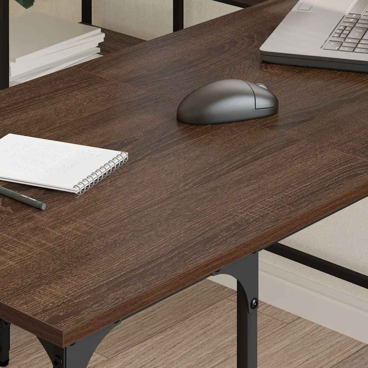 Ein brauner Holzschreibtisch mit Laptop, Maus, Notizblock und Stift. Der Schreibtisch hat ein schwarzes Metallgestell.