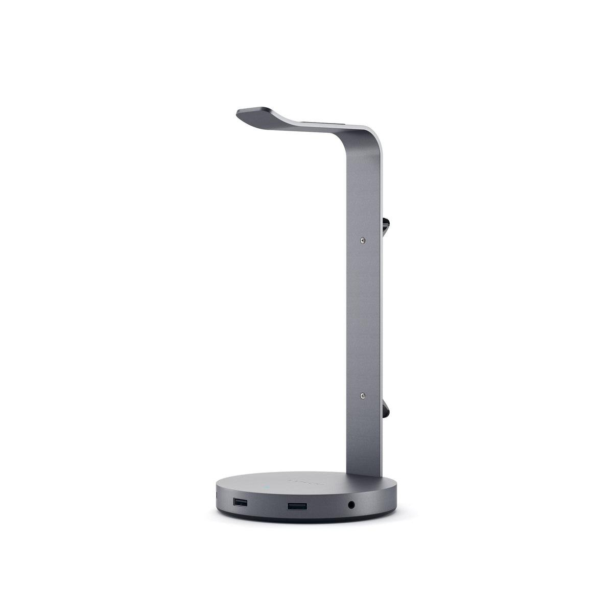 Un supporto per cuffie grigio con base circolare, colonna verticale e parte superiore curva. Porte USB sulla base.