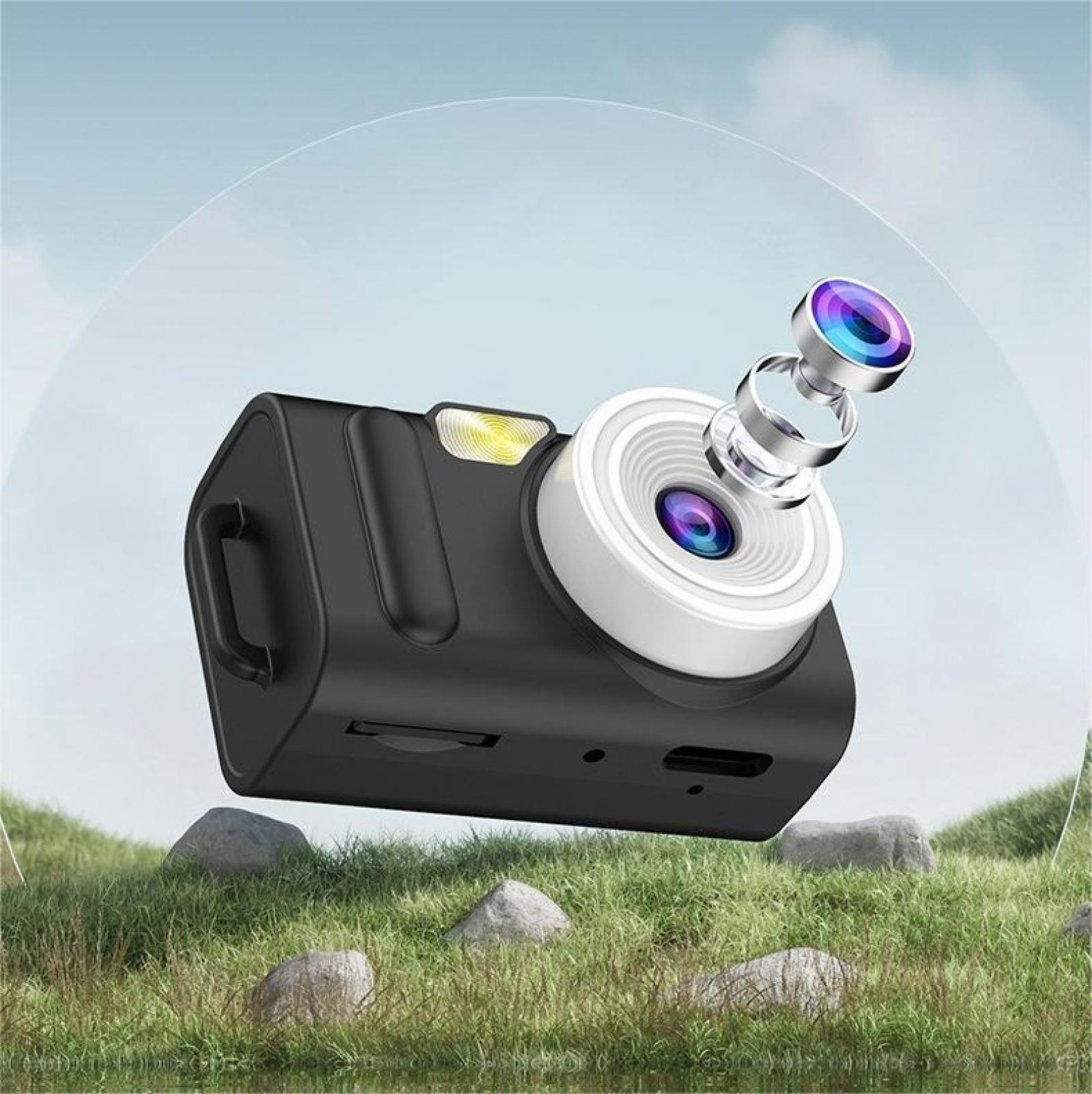 Eine schwarze Kamera mit weißem Objektiv steht auf einer grasbewachsenen Oberfläche. Sie hat ein abgenommenes Objektiv. Der Hintergrund ist ein blauer Himmel.