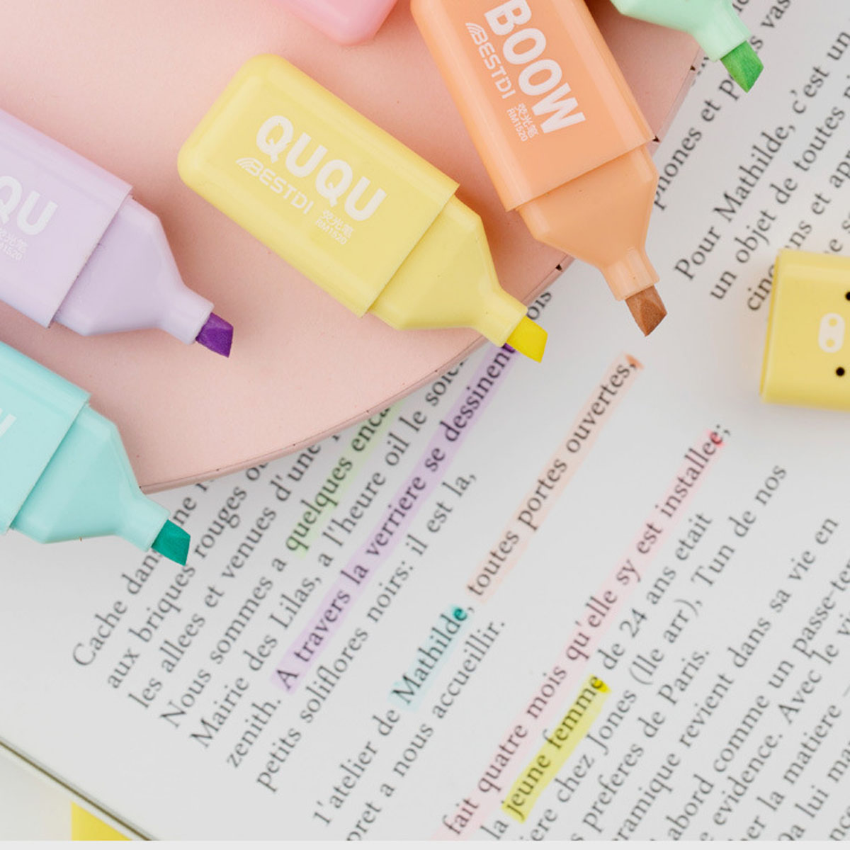 Nahaufnahme von bunten Textmarkern auf einem Buch, das Text hervorhebt. Verschiedene Farben: lila, gelb, orange und grün.