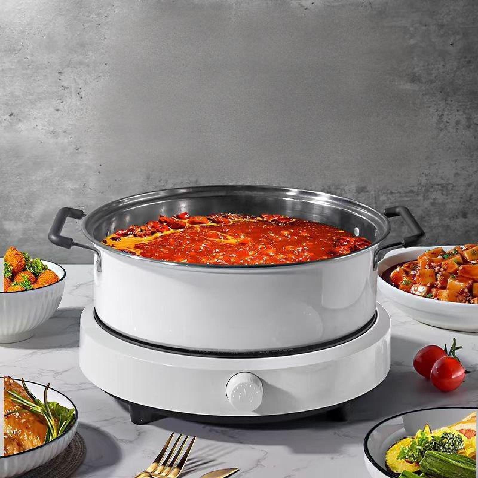 Weißer Topf mit roter Soße auf einem weißen Brenner, umgeben von Schüsseln mit Essen und Tomaten auf Marmor.