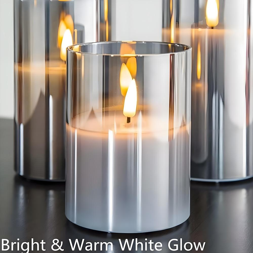 Drei brennende Kerzen in Glashaltern. Flammen leuchten hell. Die Halter sind reflektierend und stehen auf einer dunklen Oberfläche.