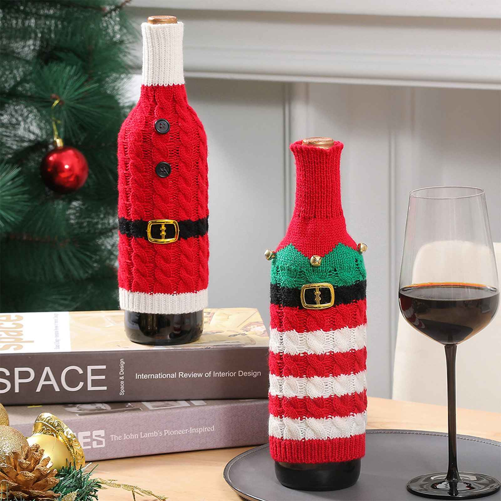 Zwei Weinflaschen in Weihnachtspullover-Hüllen. Einer ist Santa, der andere ist ein Elf. Rechts ist ein Weinglas.