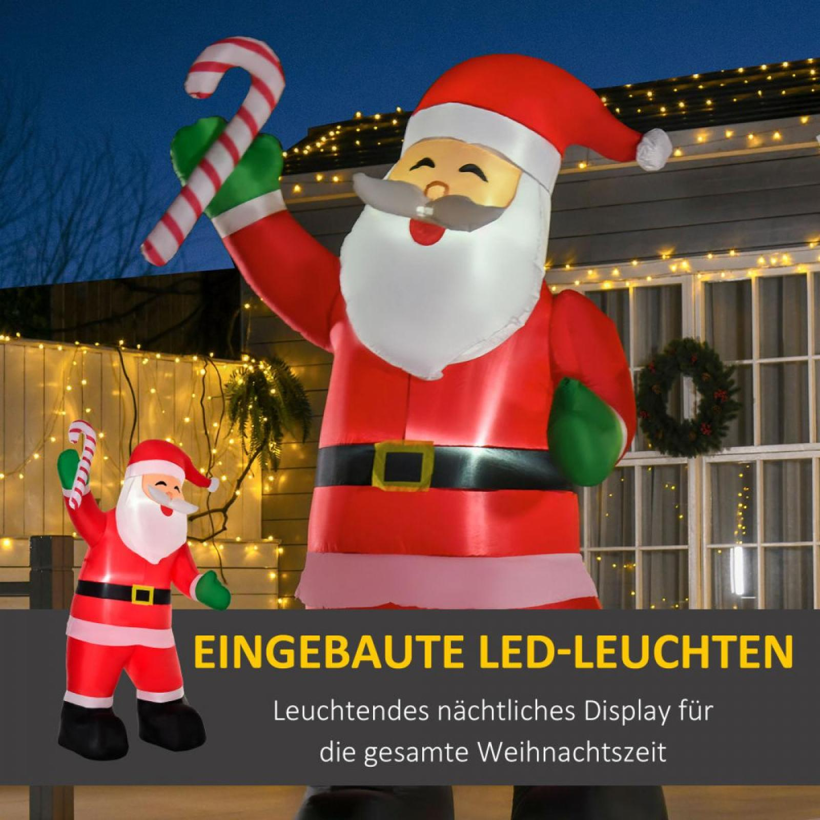 Aufblasbarer Weihnachtsmann mit Zuckerstange. Ein weiterer kleinerer Weihnachtsmann steht davor. Lichterketten und ein Kranz sind sichtbar.