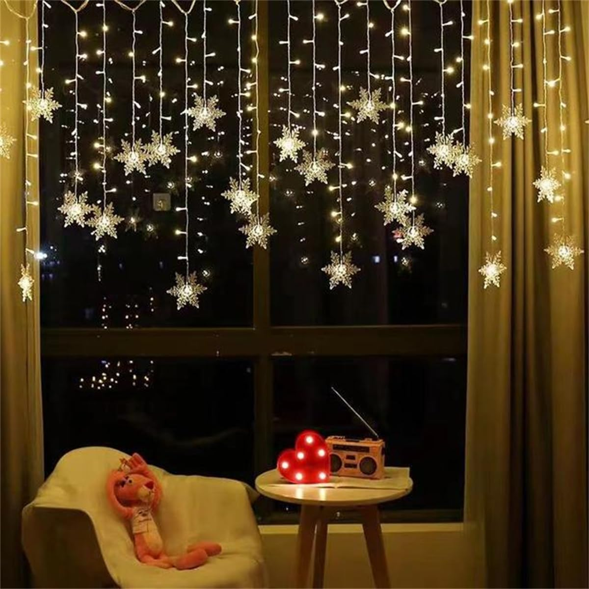 Ein Raum mit Schneeflockenlichtern, einem Fenster, einem Stuhl mit einem Plüschtier und einem Tisch mit Herzlicht und Radio.