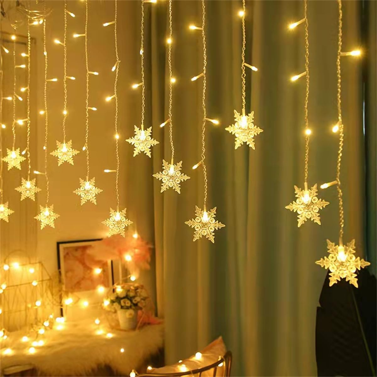 Lichterketten mit Schneeflocken-Ornamenten hängen vor einem grünen Vorhang. Ein warmes Leuchten erhellt die Szene.