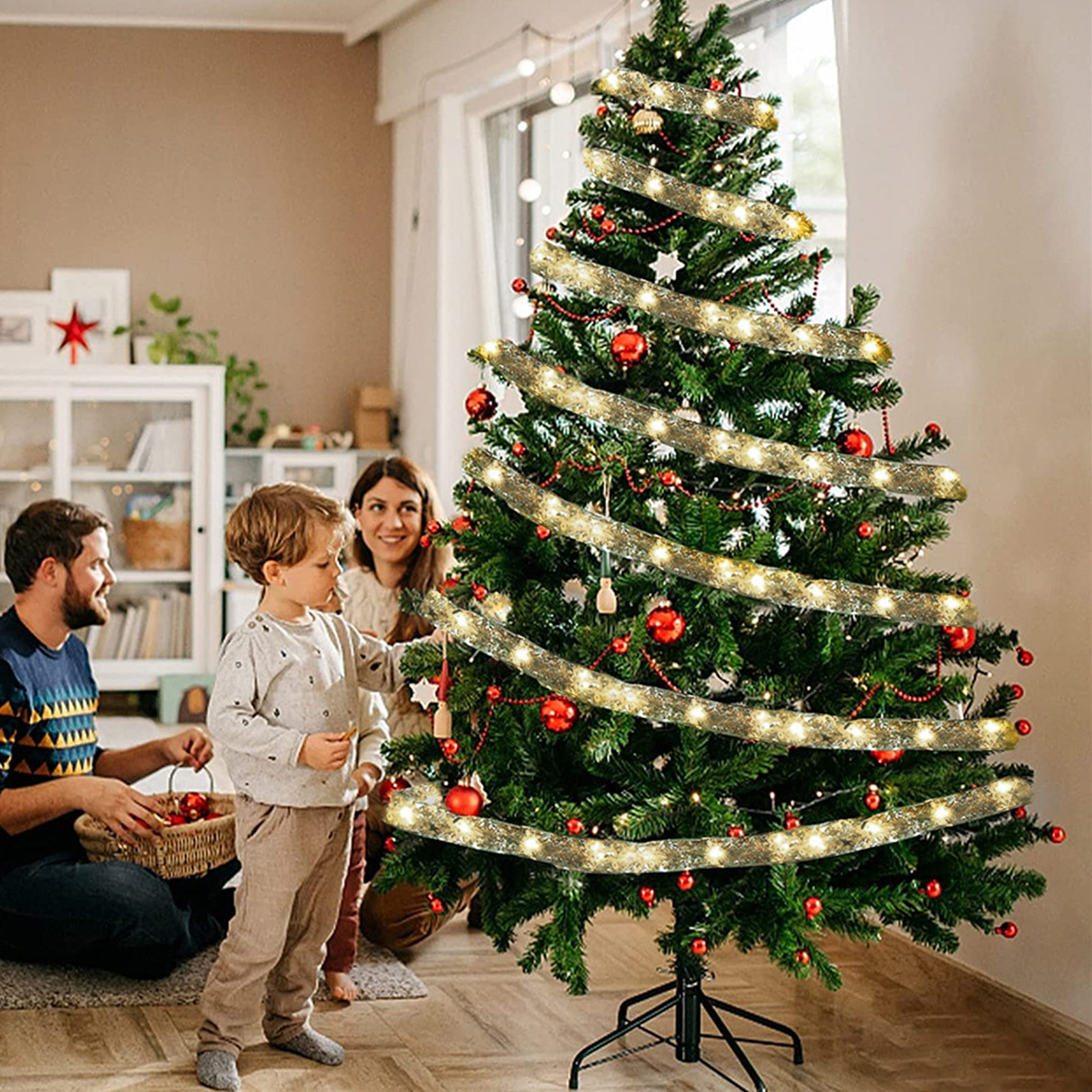 Familie schmückt einen Weihnachtsbaum. Schmuck und Lichter sind am grünen Baum. Ein Kind und Eltern sind zusammen.