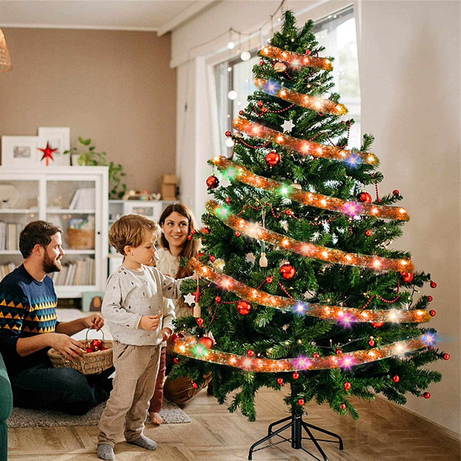 Eine Familie schmückt einen Weihnachtsbaum mit Ornamenten und Lichtern. Ein Mann, eine Frau und ein Kind sind versammelt.