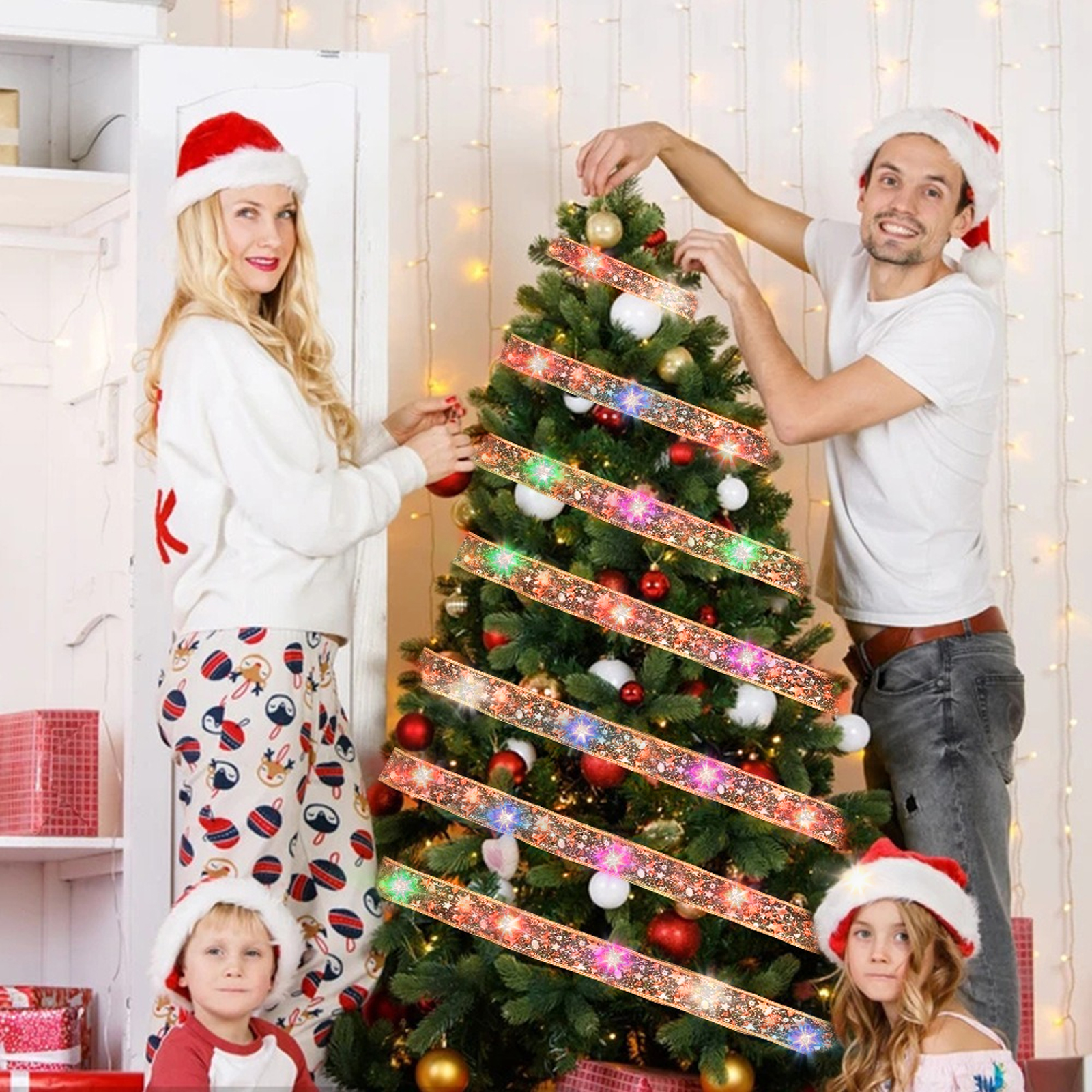 Familie schmückt einen Weihnachtsbaum. Menschen tragen Weihnachtsmützen. Baum hat Lichter und Ornamente. Geschenkboxen im Vordergrund.