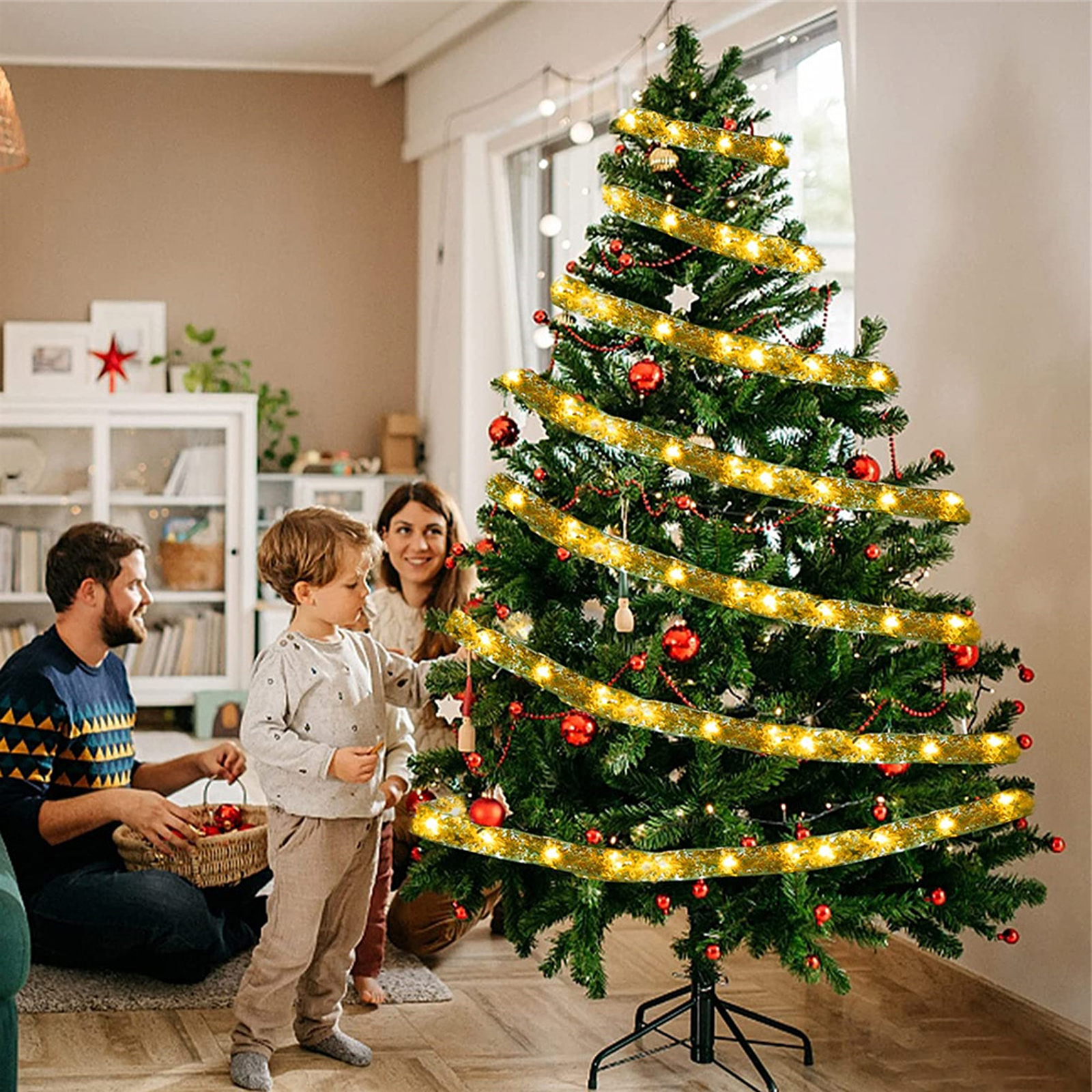 Familie schmückt einen Weihnachtsbaum. Der Baum ist mit Lichtern, Ornamenten und Girlanden geschmückt. Ein Kind hilft.
