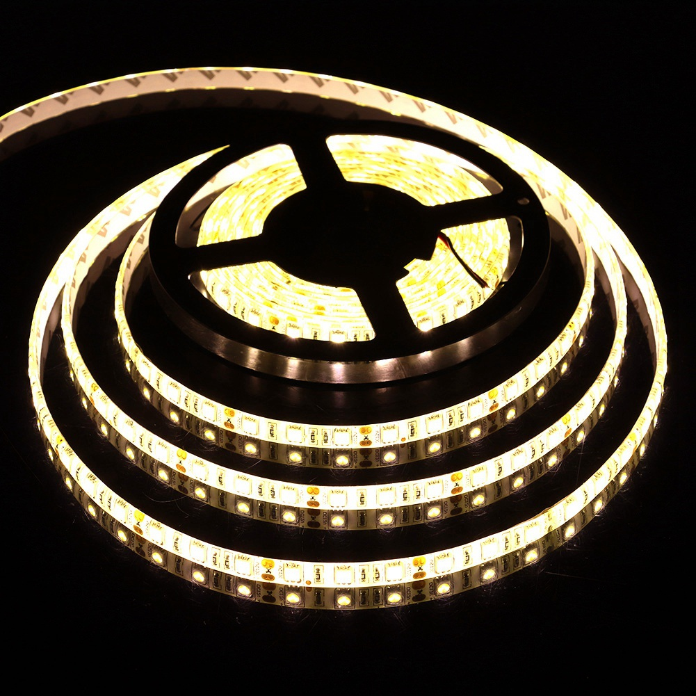 Eine Rolle LED-Streifen, die ein warmweißes Leuchten aussenden, wird vor einem schwarzen Hintergrund abgerollt. Die Lichter sind an.