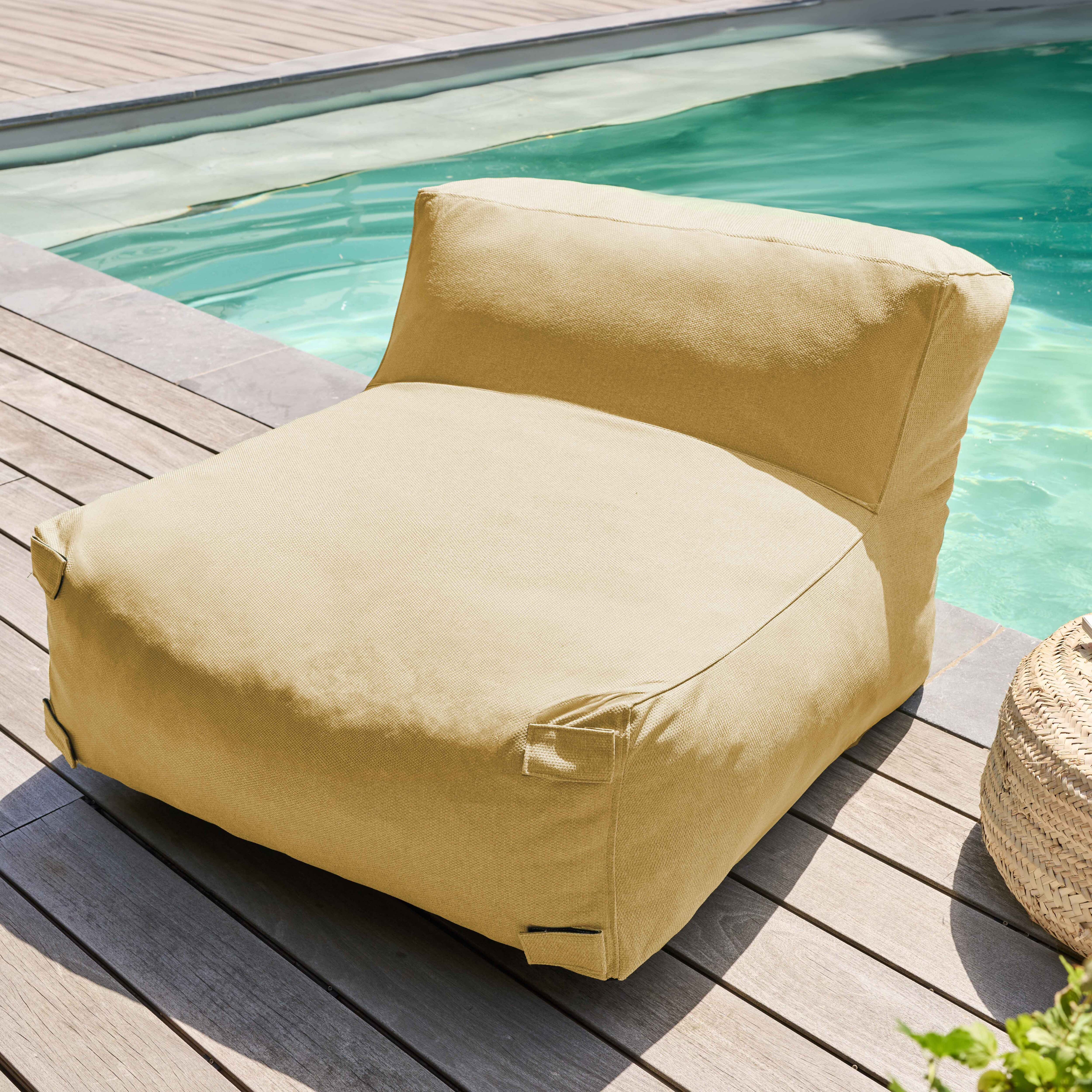 Ein beiger Sitzsack steht auf Holzterrasse neben einem Pool. Ein geflochtener Korb ist rechts.