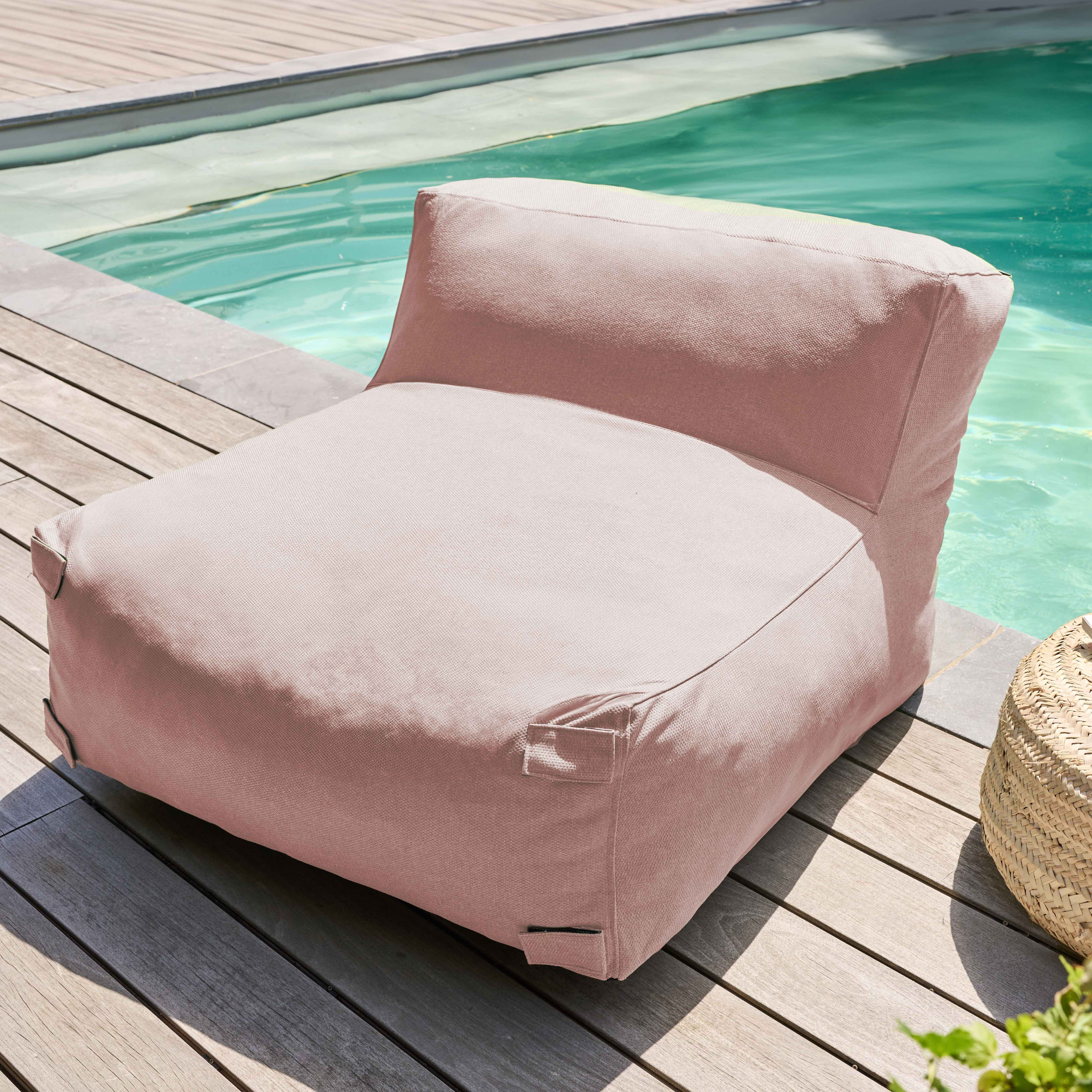 Ein rosa Sitzsackstuhl steht auf Holzterrasse neben einem Pool. Ein geflochtener Korb ist daneben.