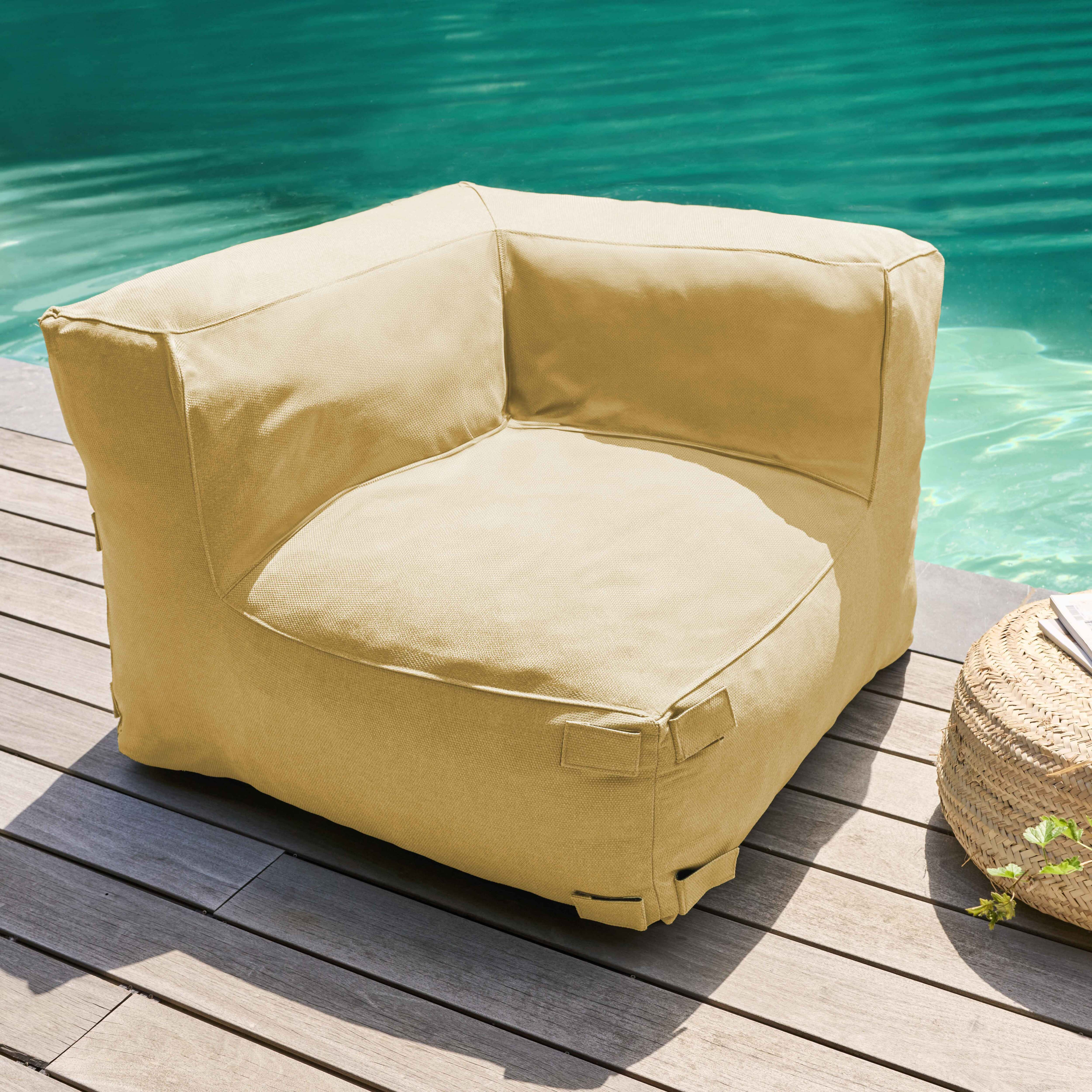 Ein beiges Ecksofa steht auf Holzterrassen neben einem Pool. Ein geflochtener Korb und Pflanzen sind in der Nähe.