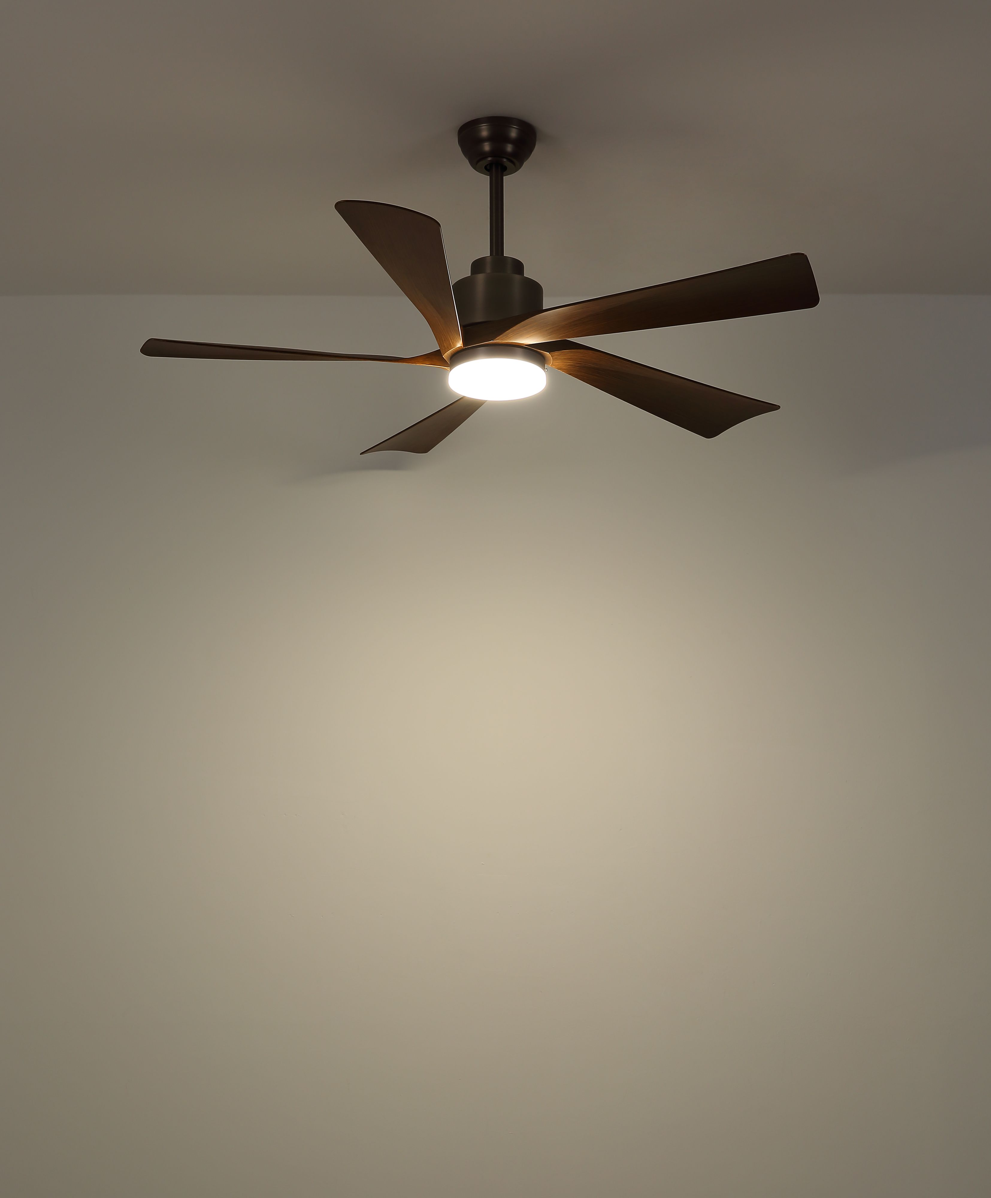 Ein Deckenventilator mit fünf braunen Flügeln und einem zentralen Licht ist an einer weißen Decke montiert.