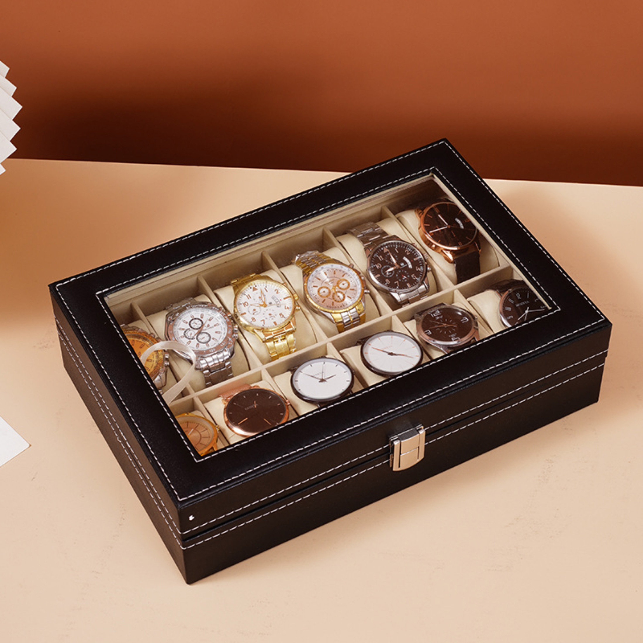 Eine schwarze Uhrenbox mit mehreren Uhren verschiedener Designs. Der Hintergrund ist ein Farbverlauf aus Braun und Beige.