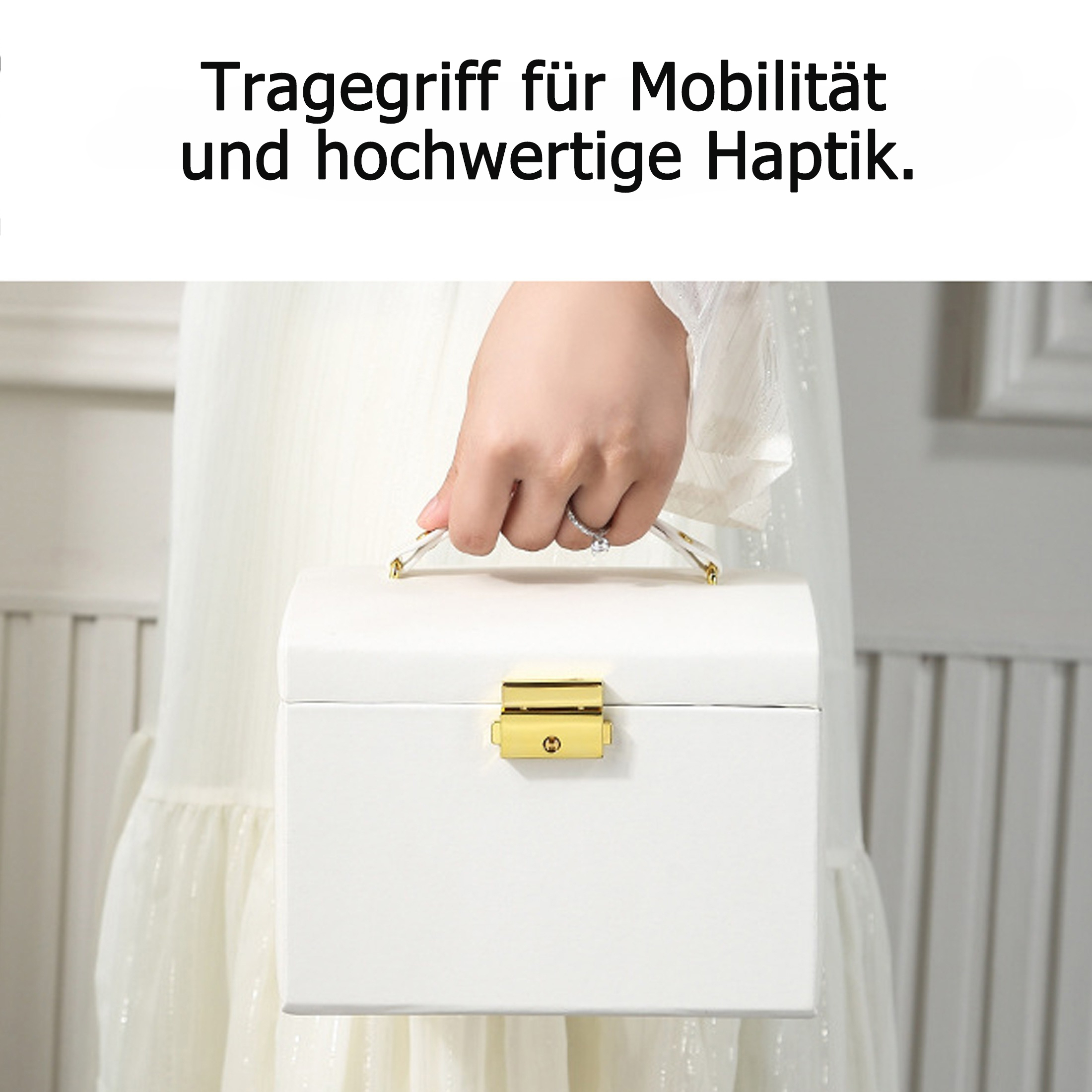 Eine Hand hält eine weiße Box mit goldenem Verschluss. Die Box hat einen Griff. Der Hintergrund ist ein verschwommenes weißes Kleid.