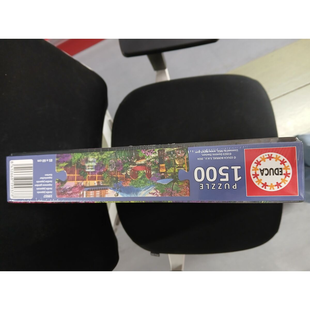 Eine Puzzledose mit einer japanischen Gartenszene. Die Schachtel liegt auf einem schwarzen Stuhl, die Marke ist Educa Puzzle 1500.
