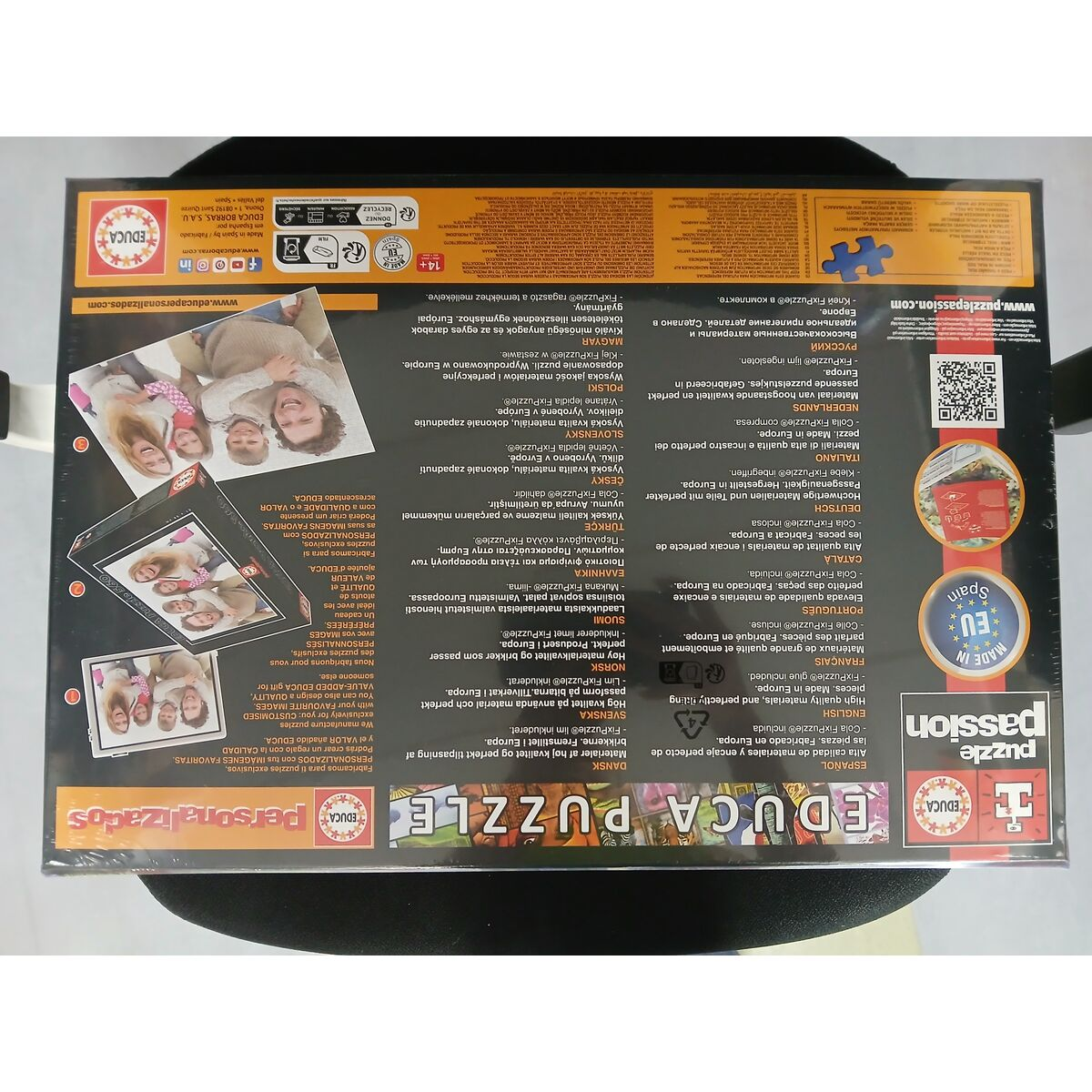 Puzzledose mit Bildern von Menschen, Text in mehreren Sprachen und Logos. Hergestellt in Spanien.