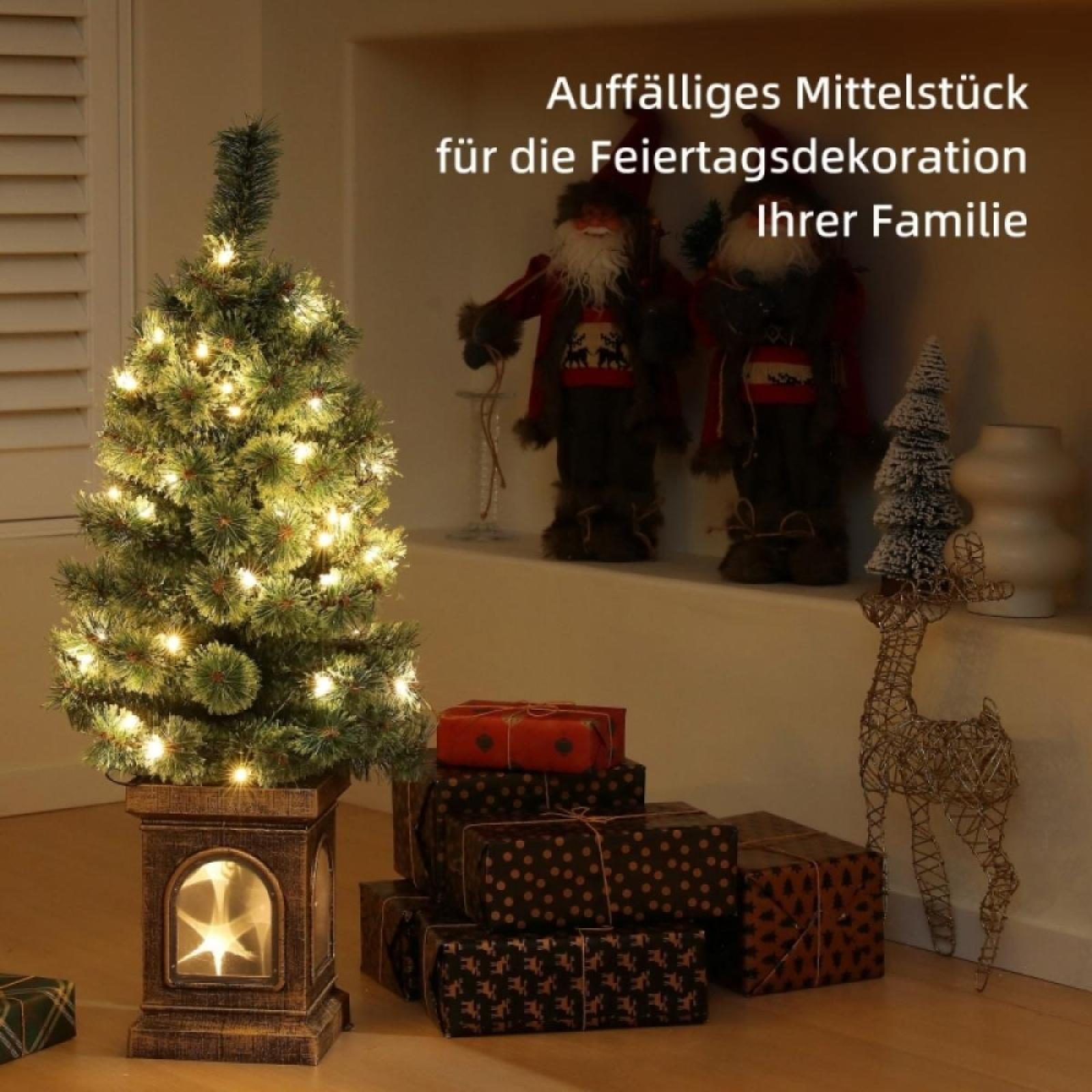 Ein beleuchteter Weihnachtsbaum, Geschenke, Santa-Figuren und ein Rentier-Ornament sind für festliche Dekoration angeordnet.