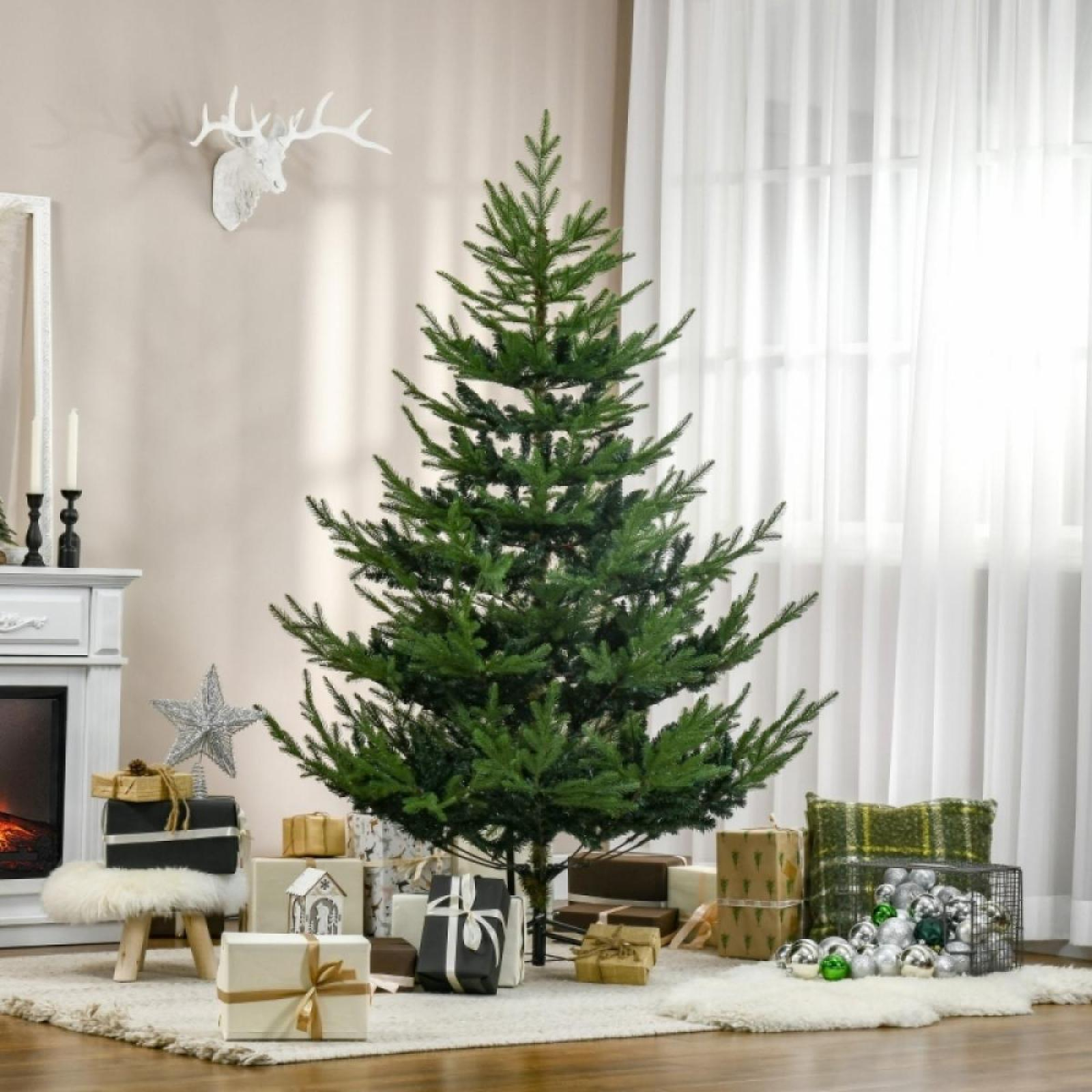 Ein geschmückter Weihnachtsbaum mit Geschenken. Ein weißer Hirschkopf an der Wand. Ein Kamin und ein Fenster sind sichtbar.