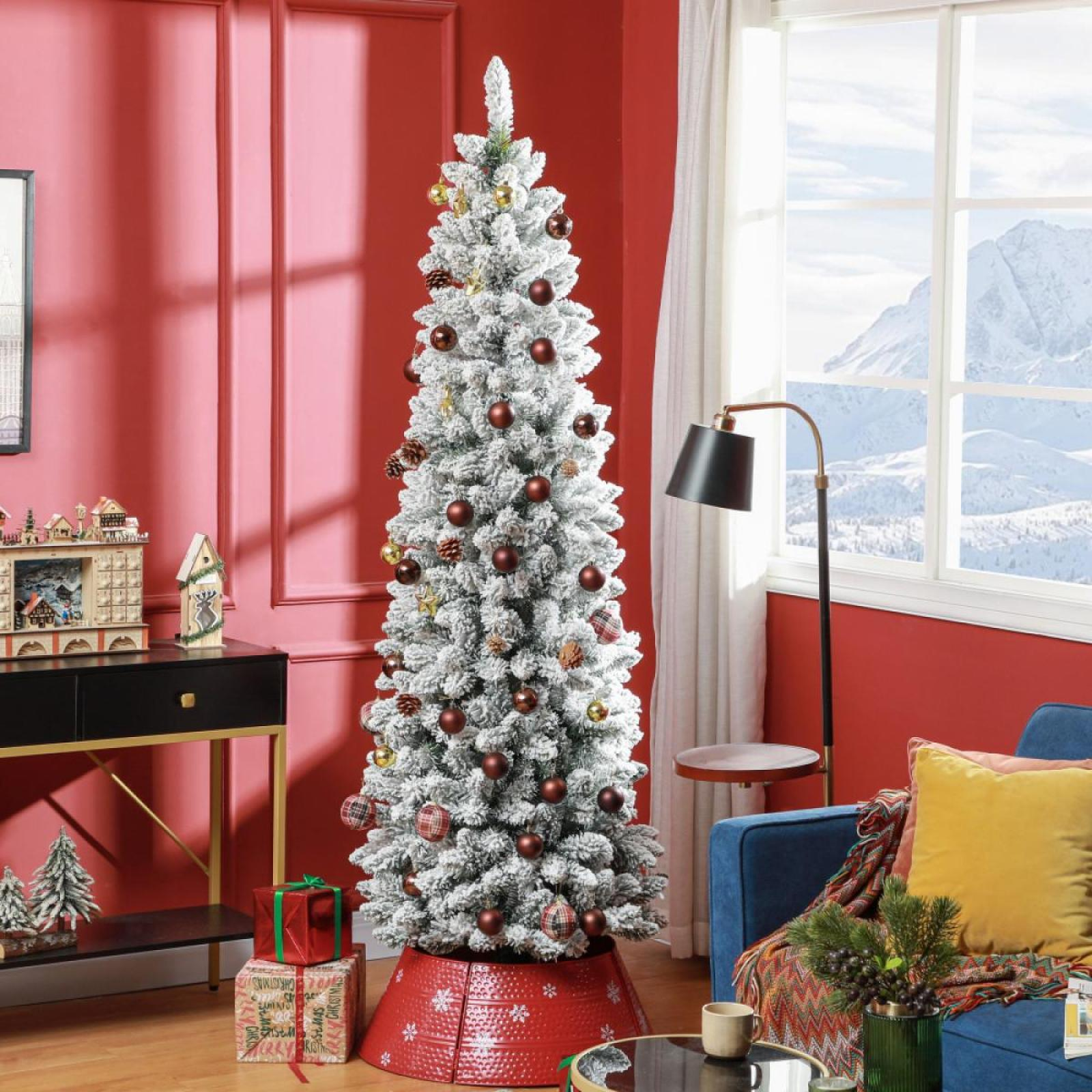 Ein geschmückter Weihnachtsbaum steht in einem Raum mit roten Wänden. Braune Ornamente und Schneeeffekt. Bergblick aus dem Fenster.