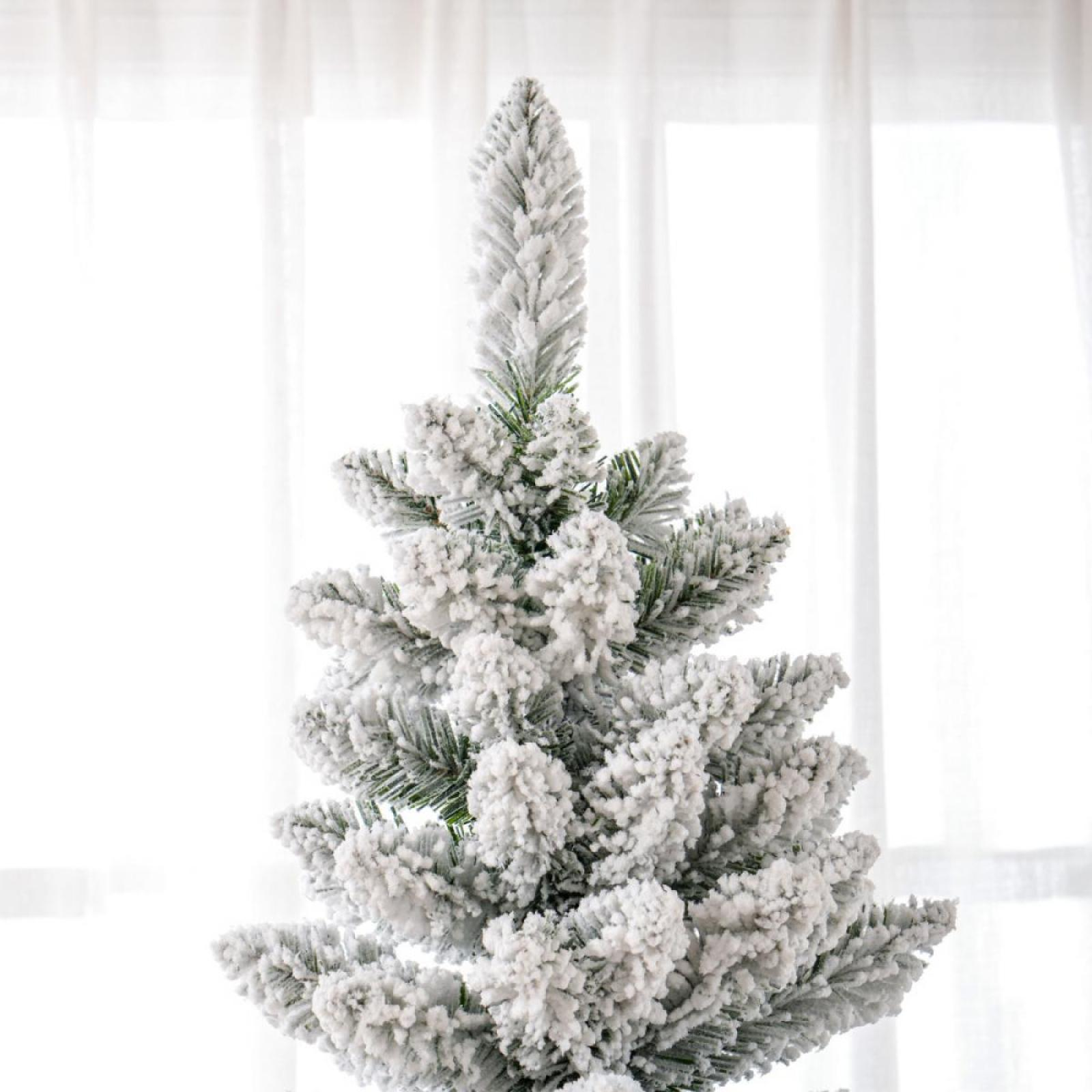 Mit Schnee bedeckter Weihnachtsbaum. Weißer Schnee bedeckt grüne Nadeln. Der Hintergrund ist ein weißer Vorhang.