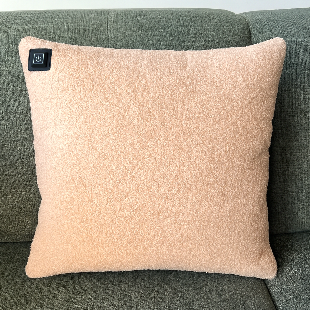 Ein pfirsichfarbenes, strukturiertes Kissen mit einem Einschaltknopf auf einer grünen Couch.