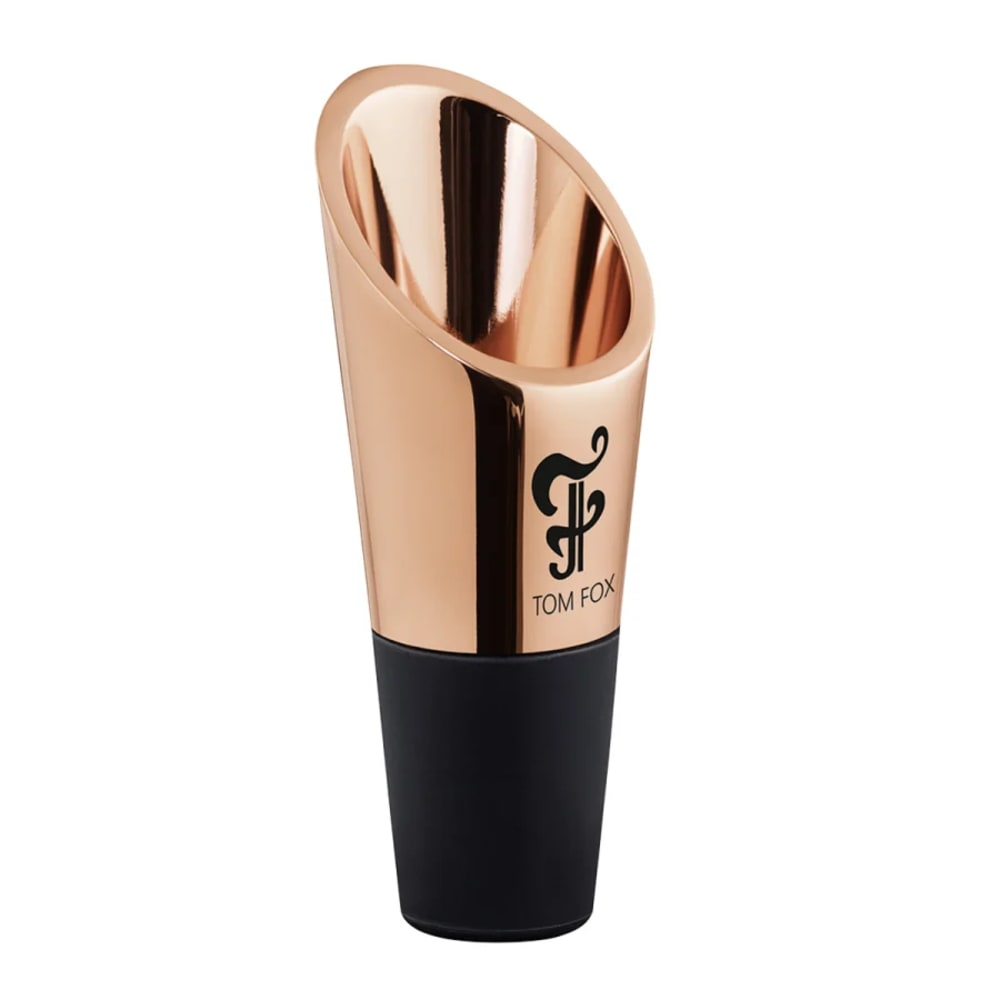 Un aeratore per vino color oro rosa con base nera. Ha un'apertura angolata e un logo che dice 'TOM FOX'.