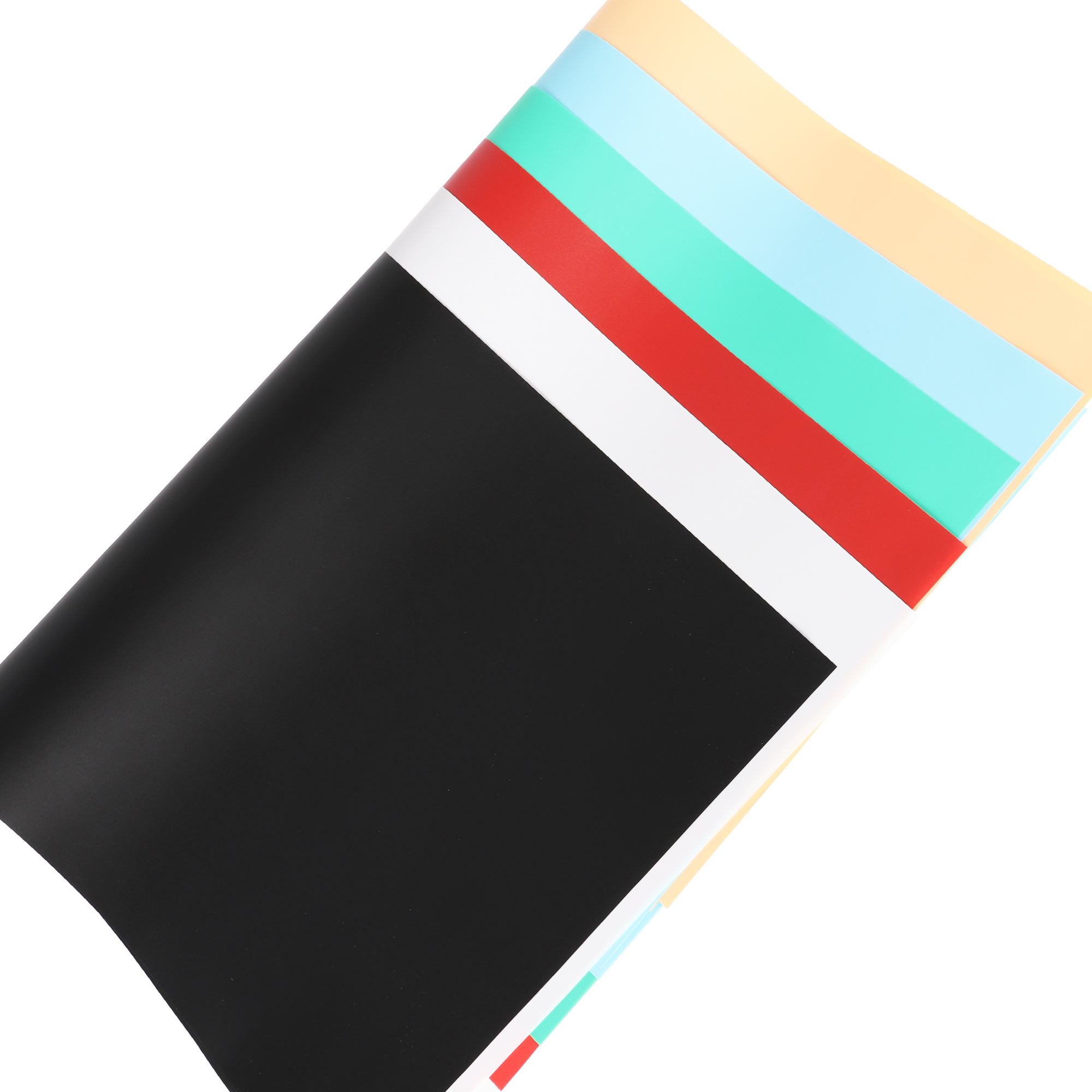 Blätter buntes Papier. Schwarz, Weiß, Rot, Grün, Blau und Beige sind sichtbar. Das Papier ist auf weißem Hintergrund abgewinkelt.