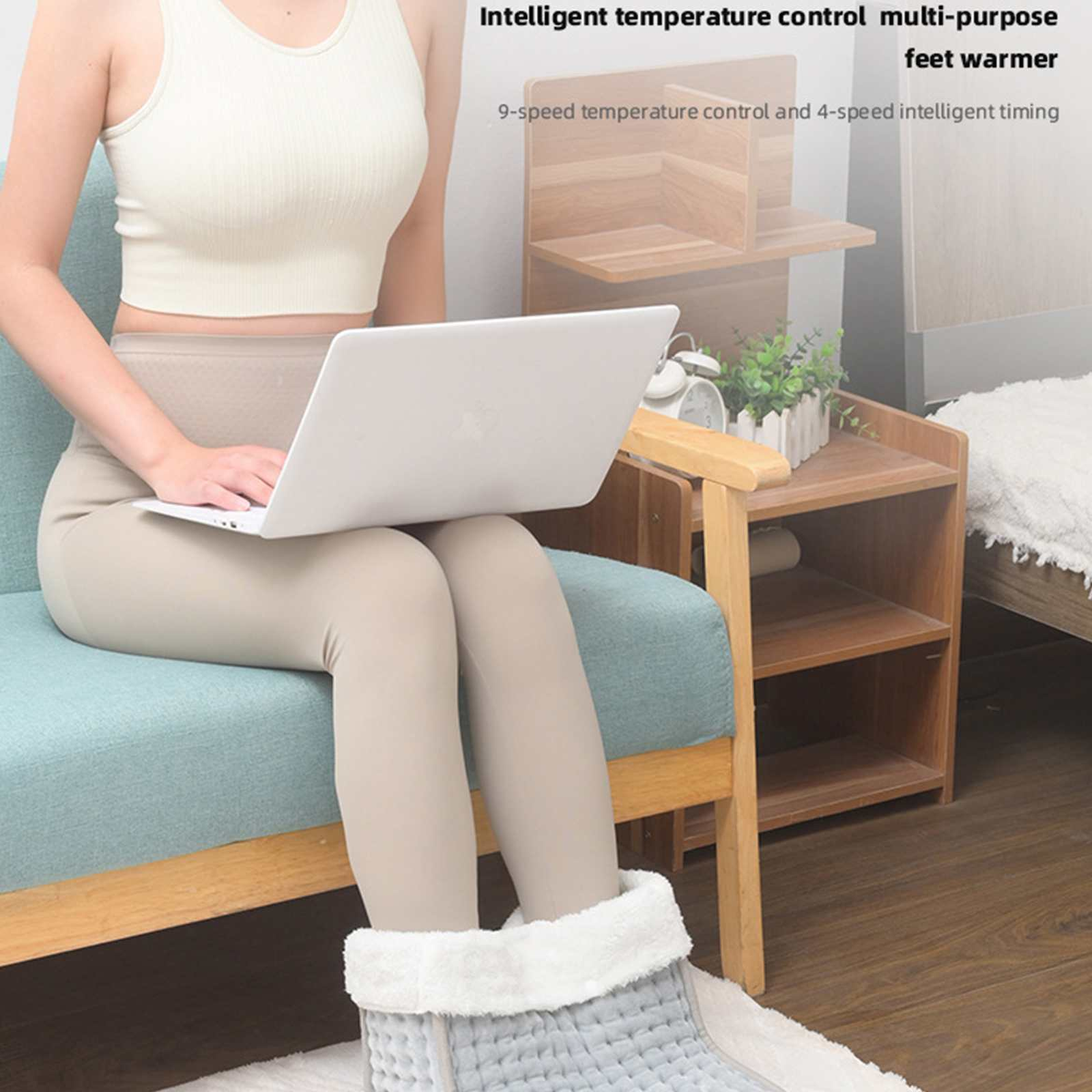 Eine Frau sitzt mit einem Laptop, die Füße in einem beheizten Fußwärmer. Produktinfo im Hintergrund.