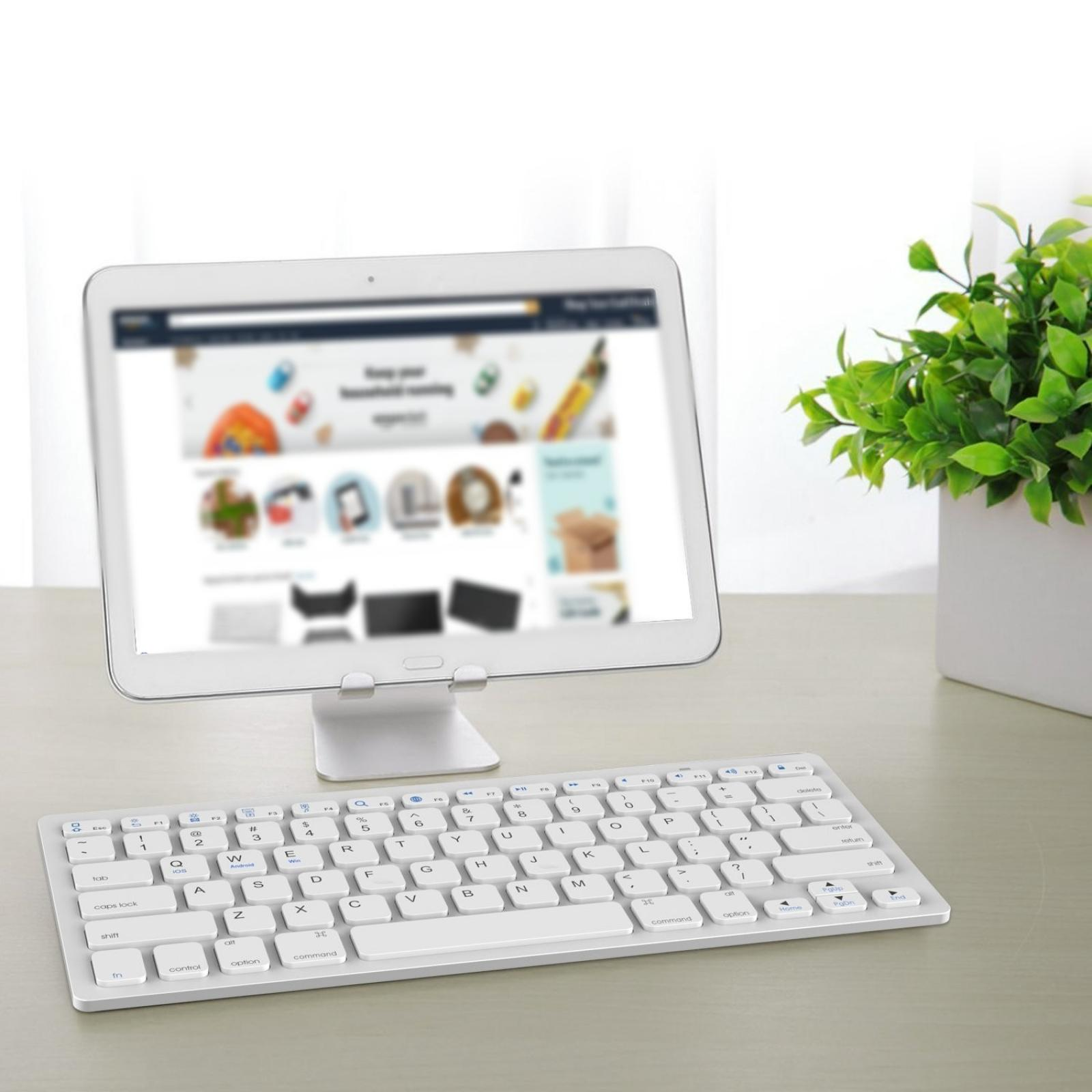 Ein Tablet auf einem Ständer und eine weiße Tastatur stehen auf einem Holztisch. Rechts eine grüne Pflanze in einem weißen Topf.
