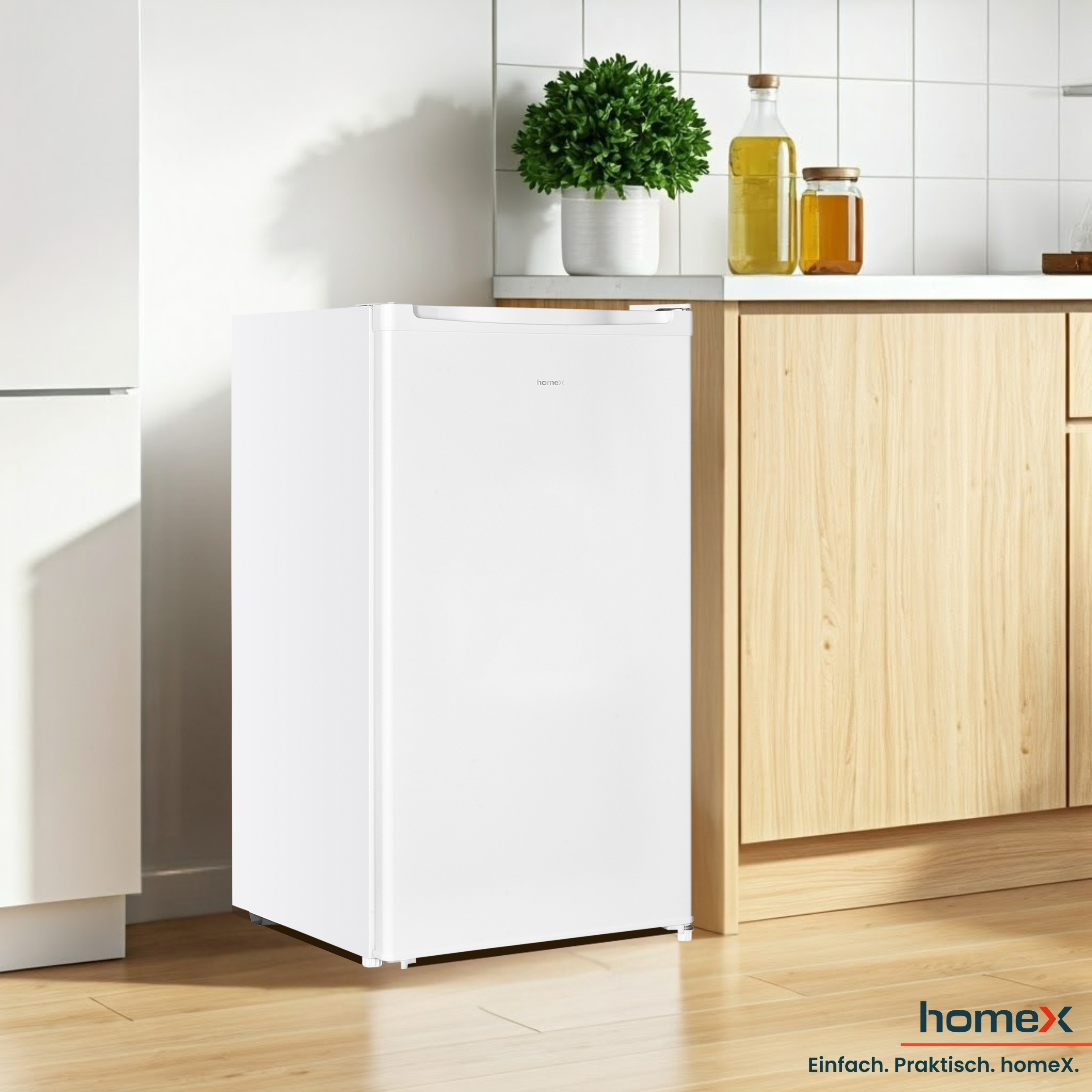 Ein weißer Mini-Kühlschrank steht neben einem Holzschrank. Auf der Theke stehen eine Pflanze, Öl und Marmeladengläser.