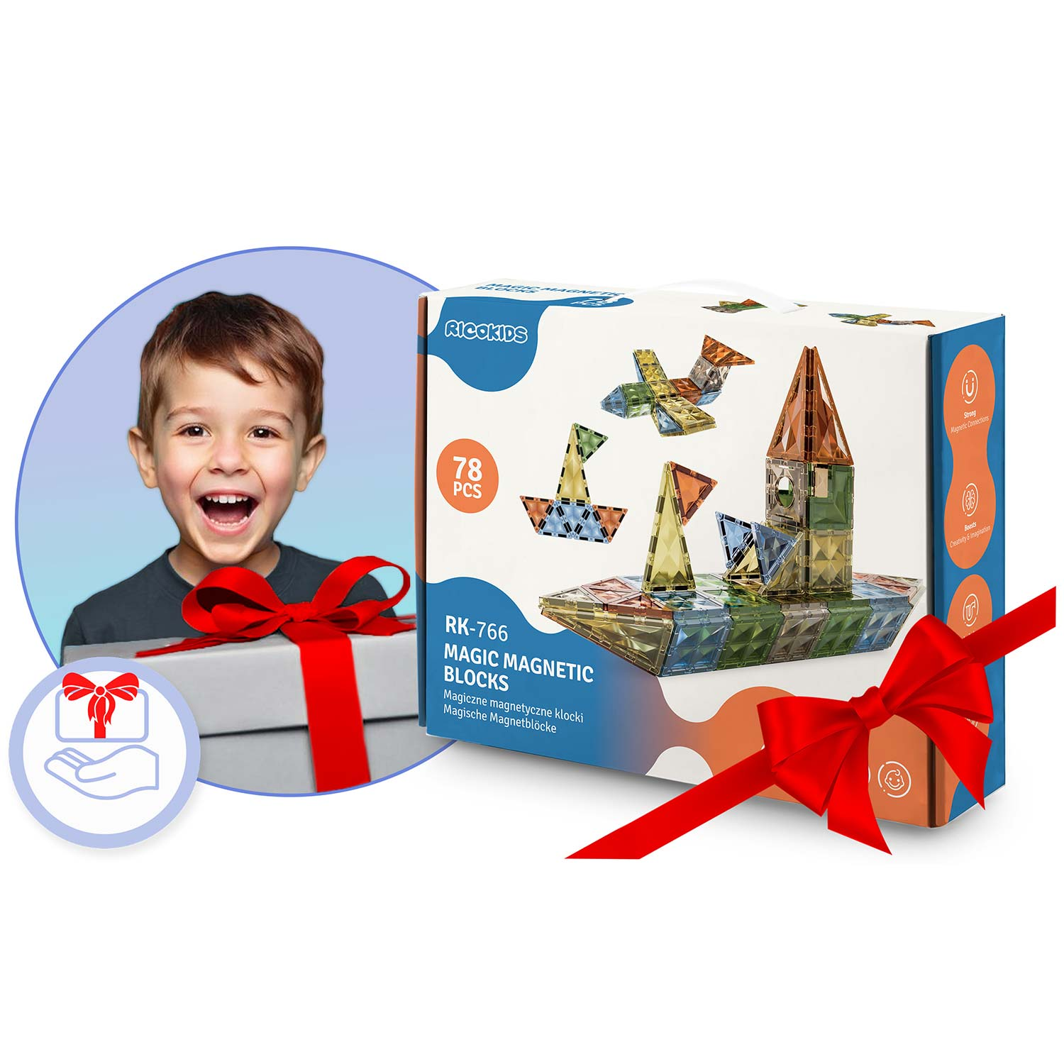 Chłopiec uśmiecha się obok pudełka prezentowego z czerwoną kokardą. Widoczna jest również skrzynka magnetycznych klocków, ozdobiona czerwoną wstążką.