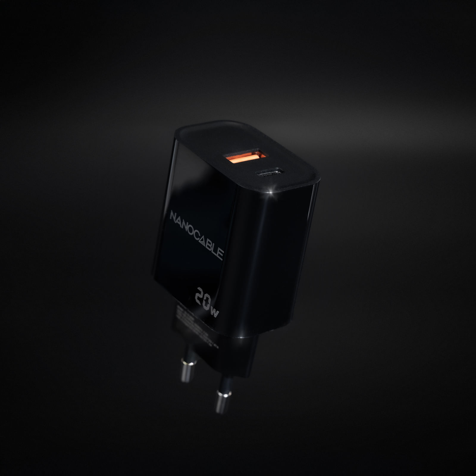 Ein schwarzes Nanocable 20W Ladegerät mit USB-C-Anschluss, orange beleuchtet. Der Hintergrund ist dunkel.