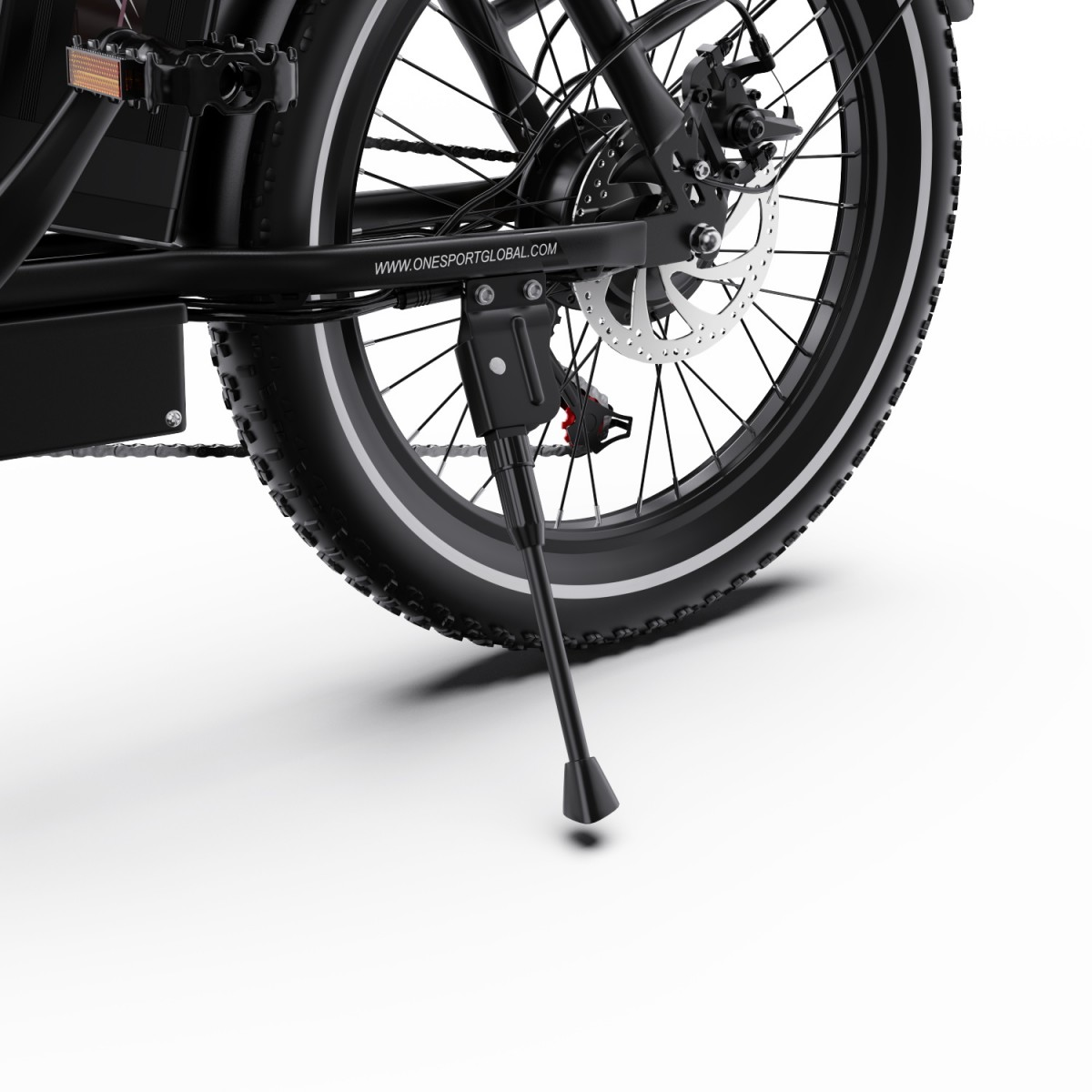 Zbliżenie czarnego koła rowerowego z hamulcem tarczowym. Podpórka podtrzymuje rower. Białe tło.