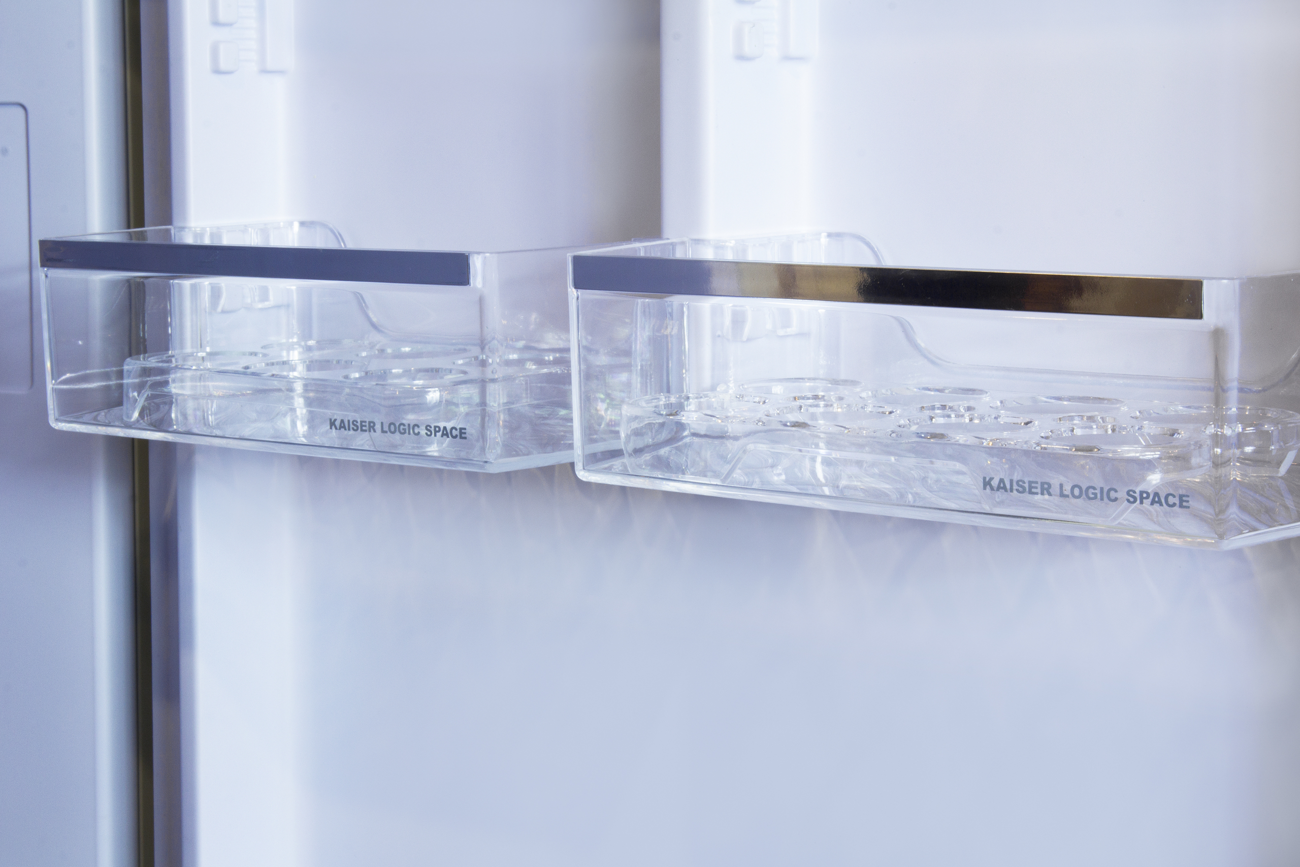 Zwei klare Plastikbehälter mit silbernen Zierleisten in einem weißen Kühlschrank. Der Text 'KAISER LOGIC SPACE' ist sichtbar.
