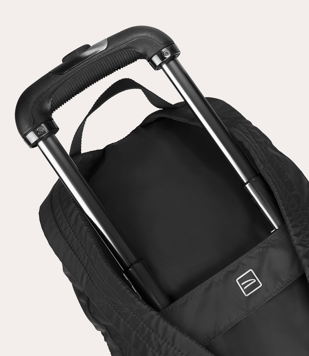 Nahaufnahme eines schwarzen Reise-Rucksacks mit ausziehbarem Griff. Der Griff ist schwarz und silber, die Tasche hat ein Logo.