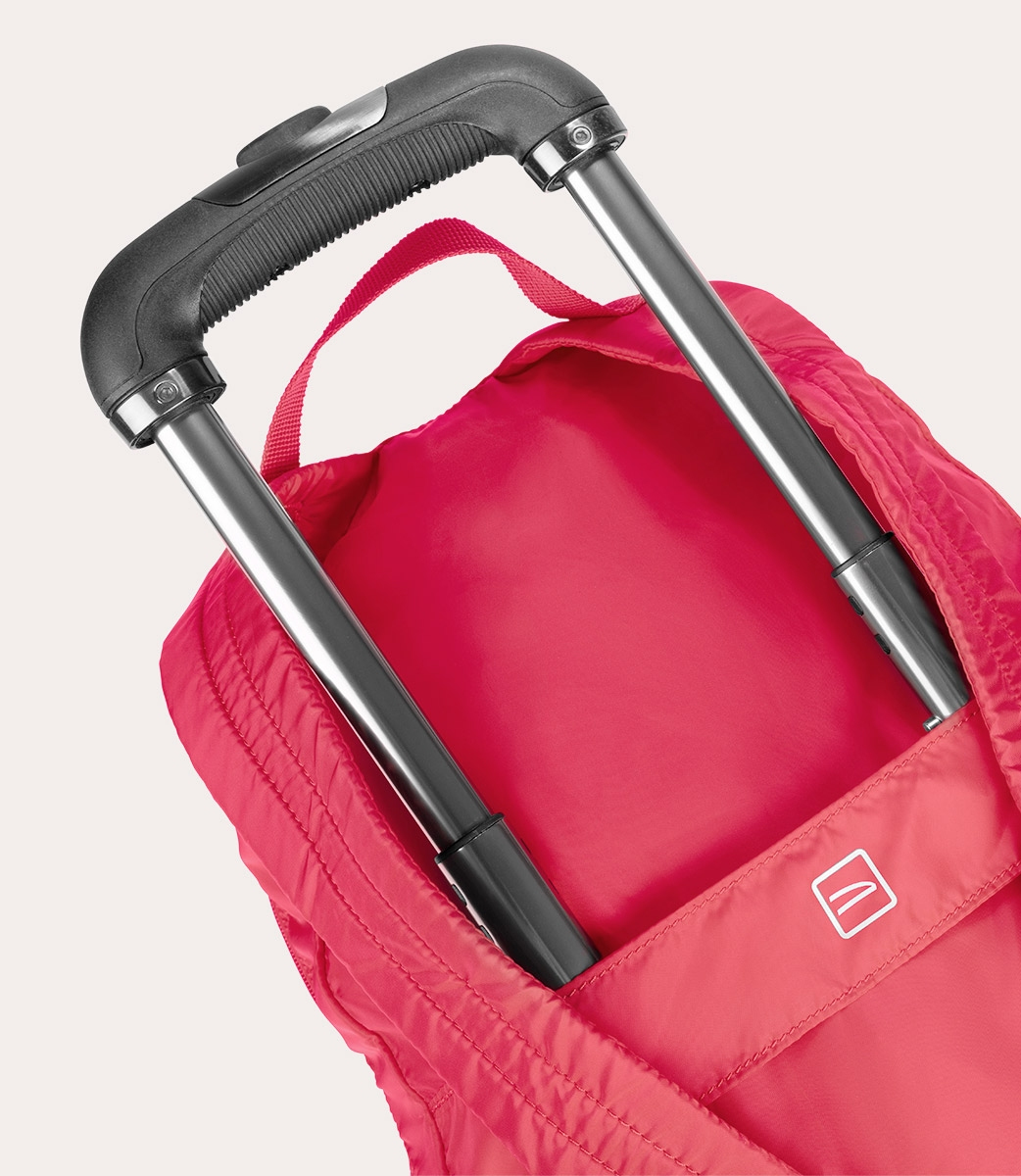 Nahaufnahme einer pinkfarbenen Reisetasche mit ausziehbarem Griff. Der Griff ist schwarz und silberfarben. Die Tasche ist offen und leer.