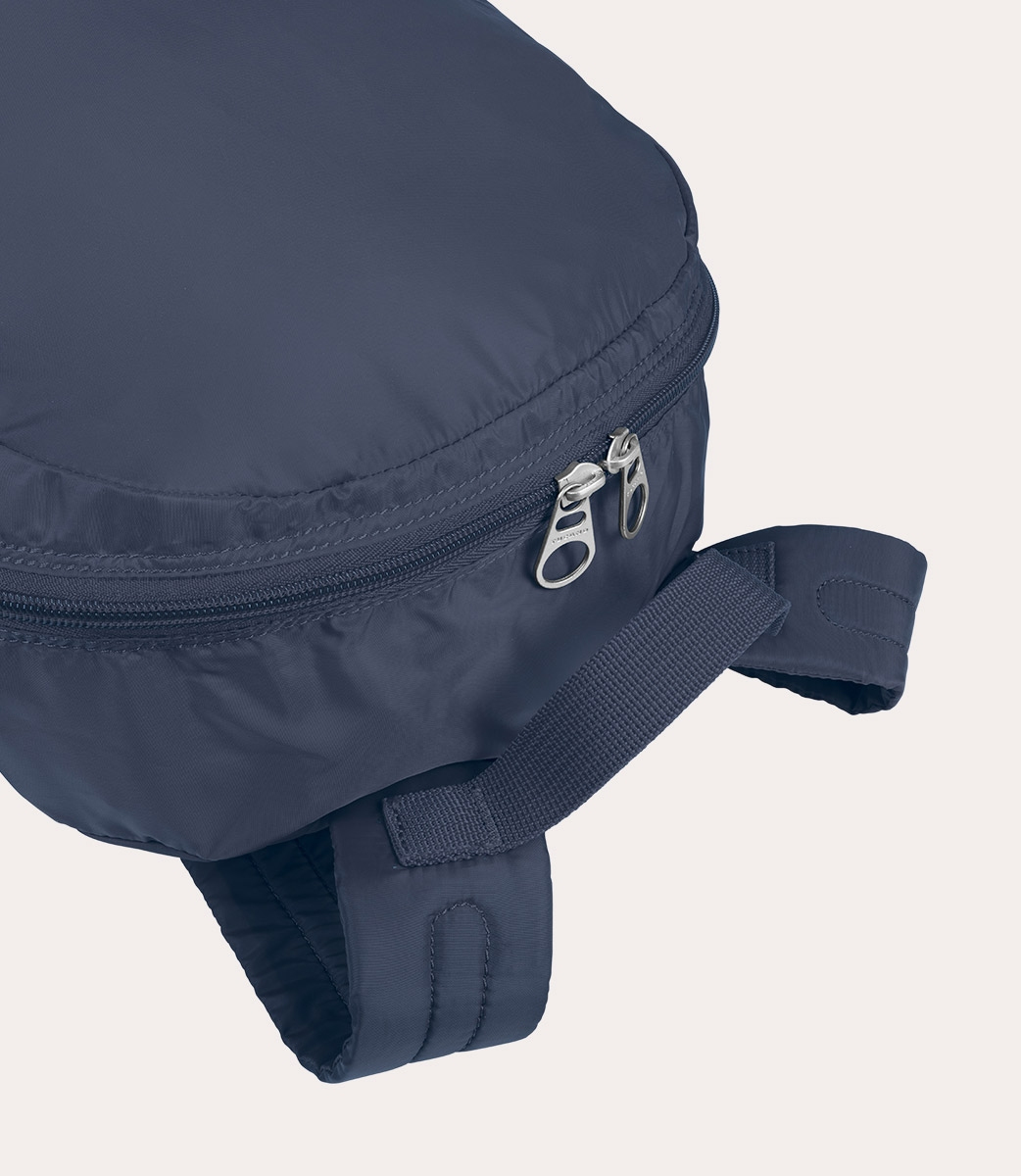 Nahaufnahme eines marineblauen, teilweise sichtbaren Rucksacks. Er hat einen Reißverschluss, einen Riemen und einen weißen Hintergrund.
