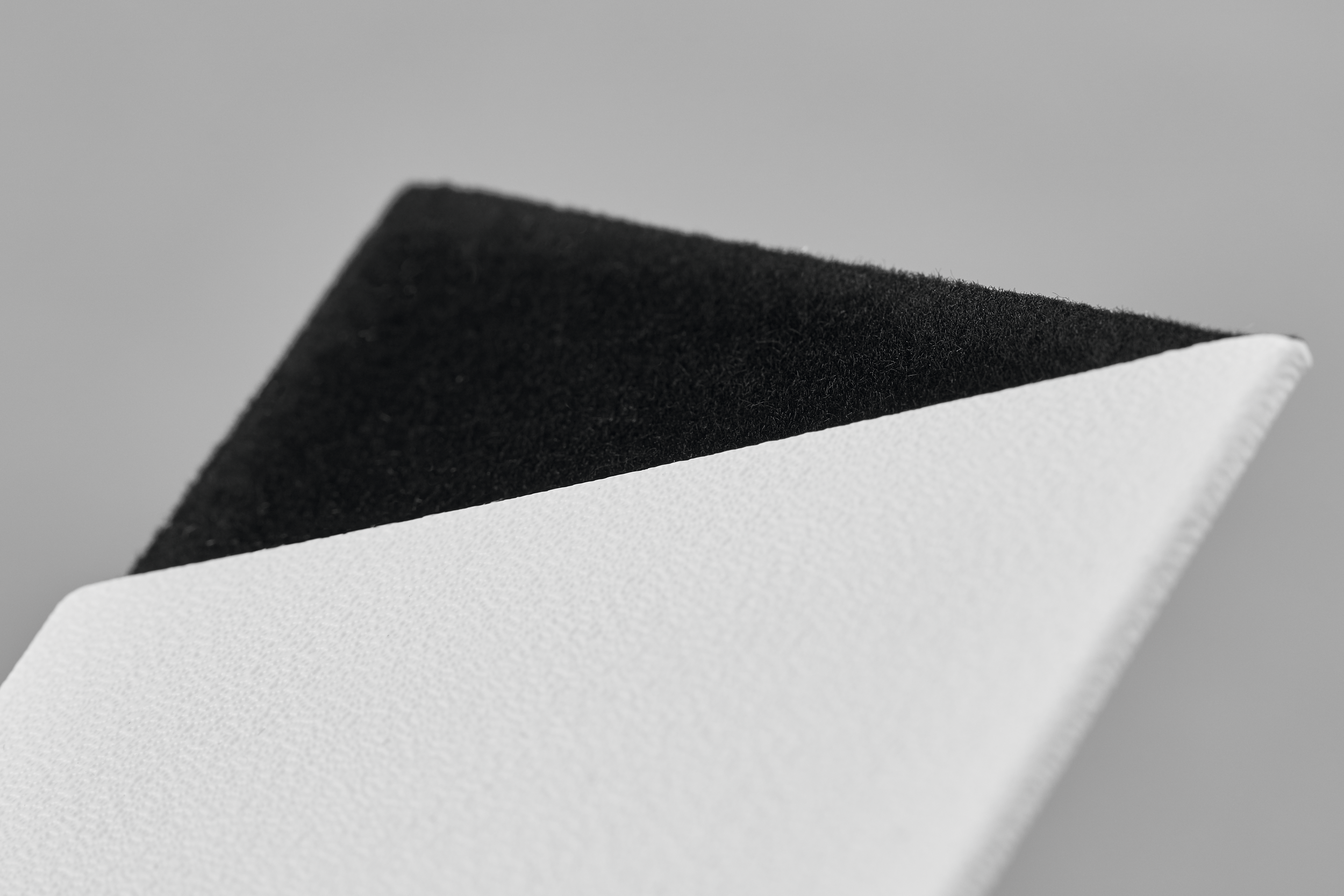 Nahaufnahme eines weißen und schwarzen strukturierten Materials vor grauem Hintergrund.