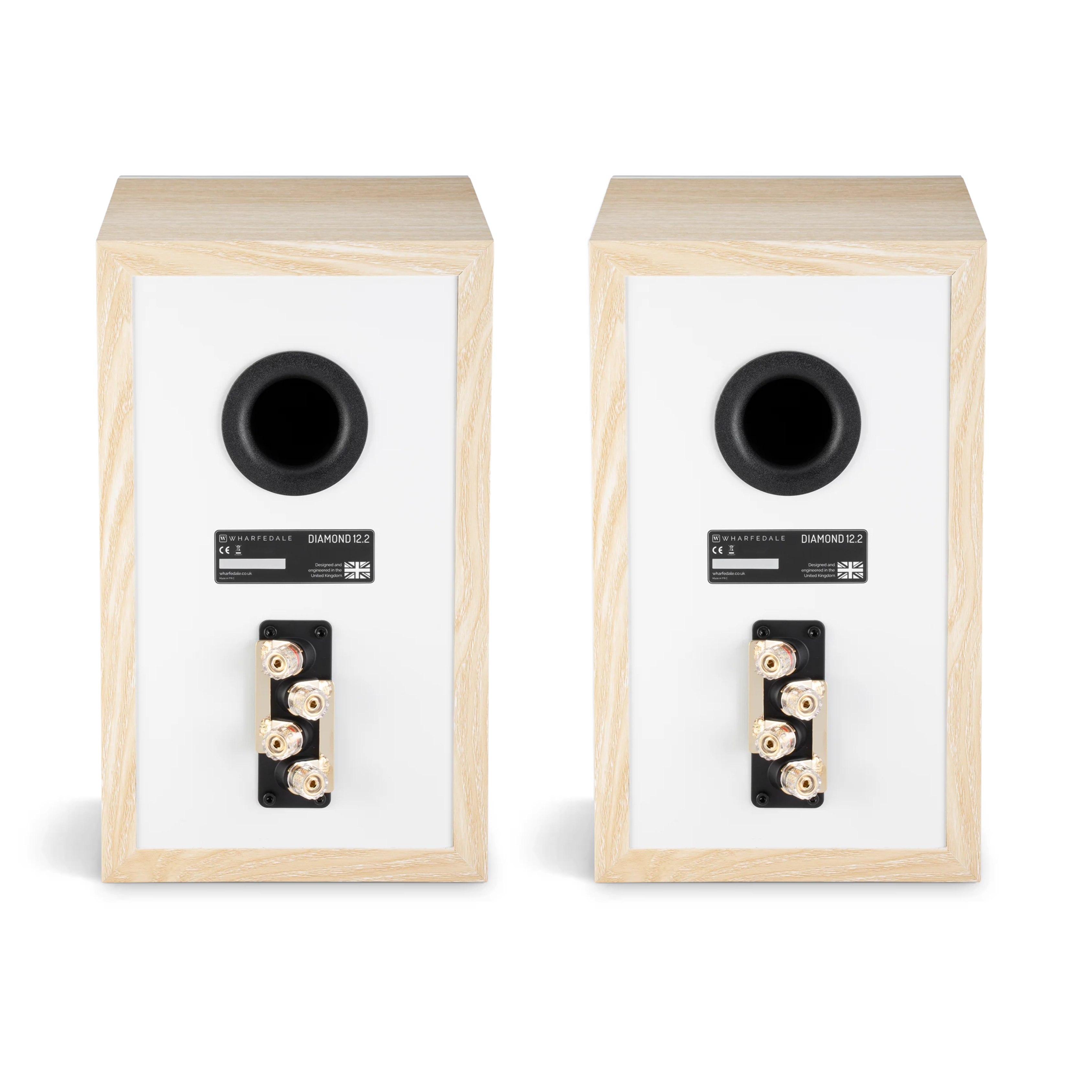 Due altoparlanti. I dorsi sono visibili. Ognuno ha un cerchio nero, connettori e una cornice in legno chiaro. Sfondo bianco.