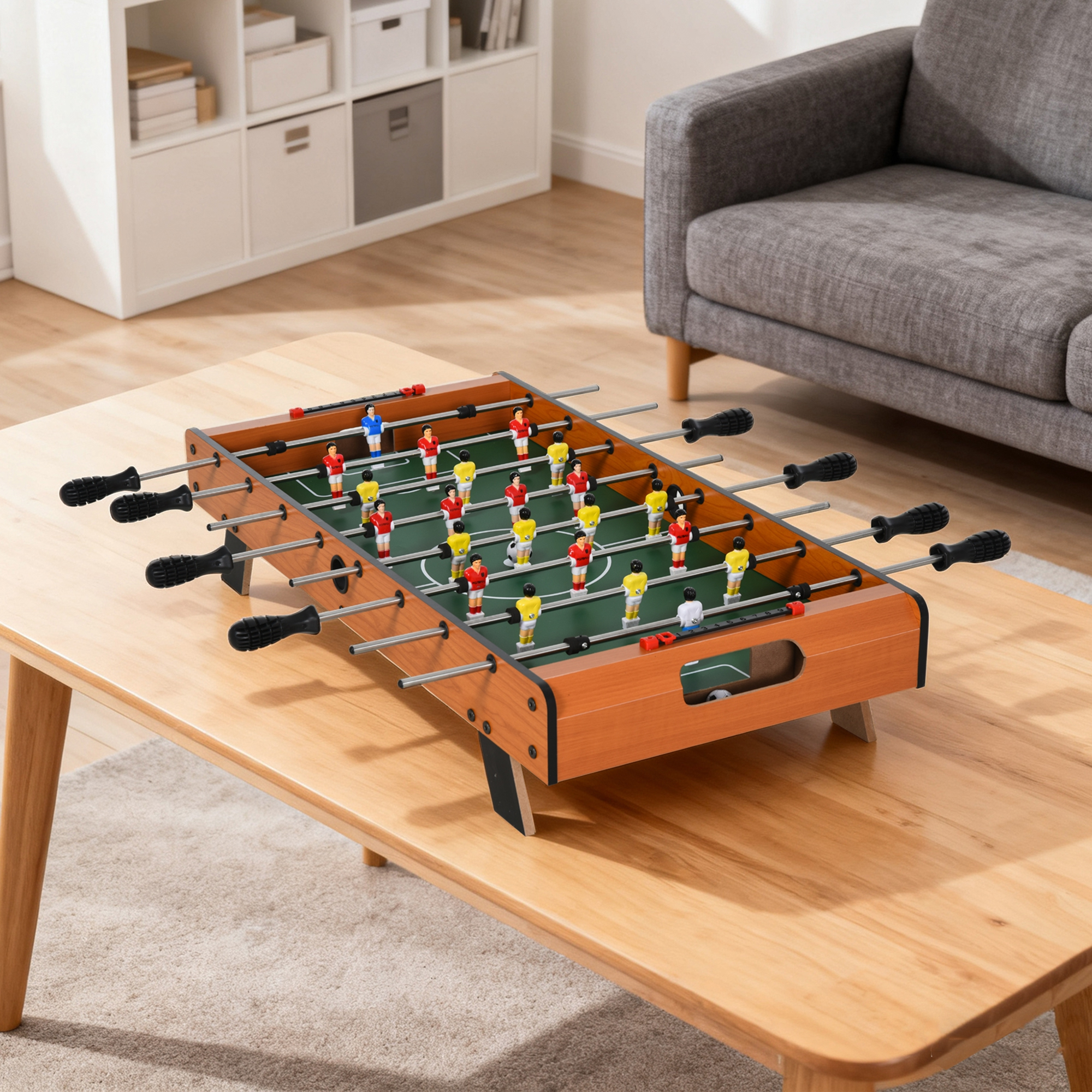 Calcio balilla su un tavolo di legno. Il gioco è pronto per essere giocato. Un divano grigio è sullo sfondo.