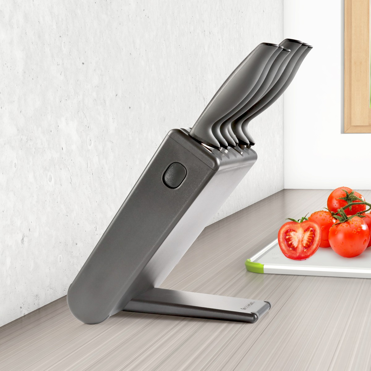 Ein Messerblock mit Messern, Tomaten auf einem Schneidebrett und einem Fenster im Hintergrund auf einer Holzoberfläche.