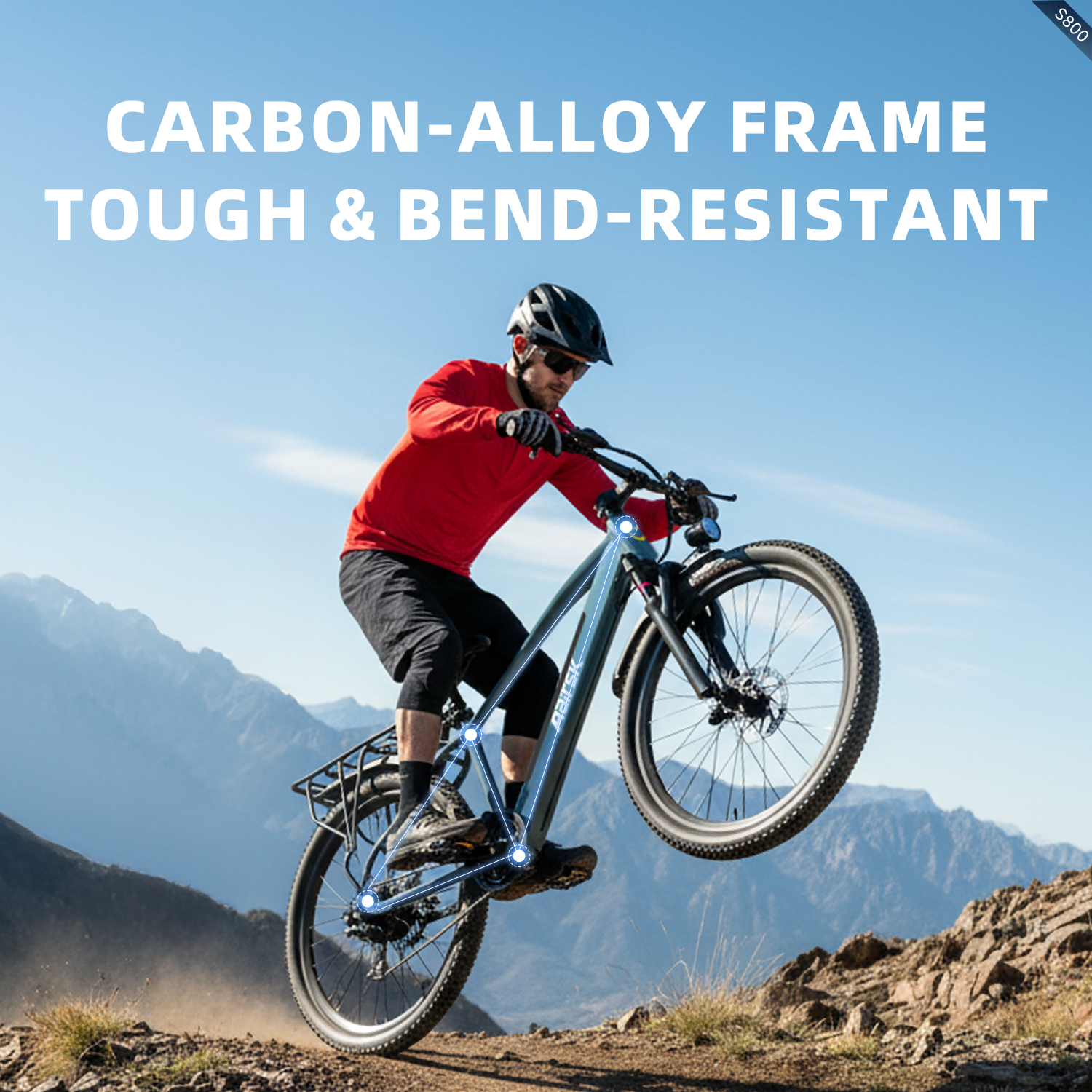 Ein Mann fährt mit einem Mountainbike in der Luft auf einem Berg. Das Fahrrad ist blau mit schwarzen Reifen. Der Mann trägt ein rotes Hemd.